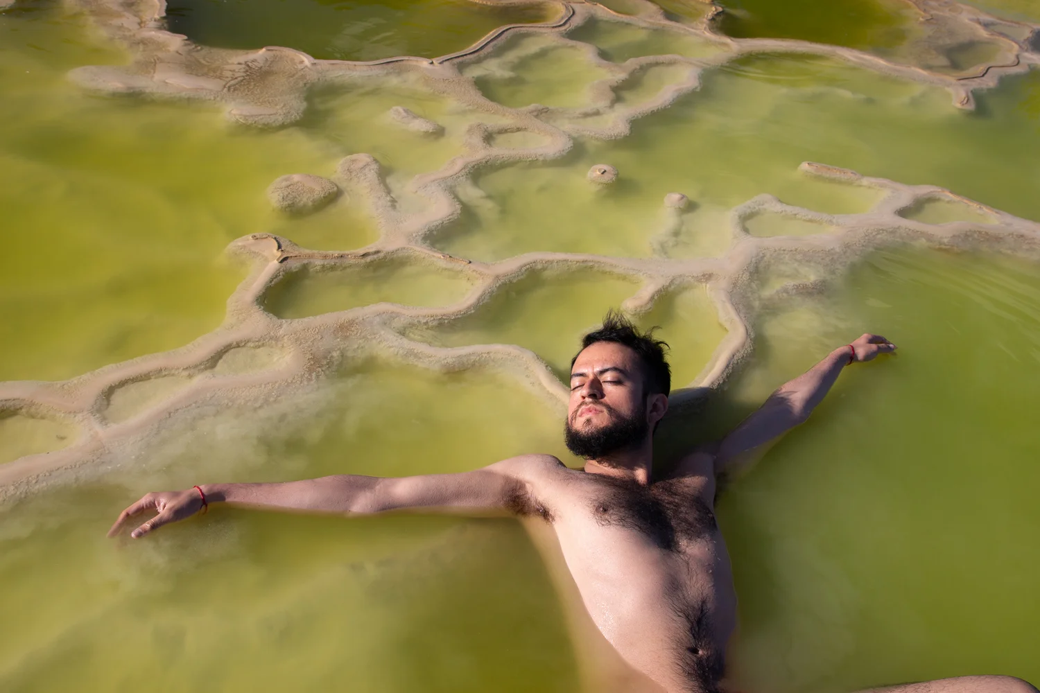 Portrait of outstretched male figure in green pool.