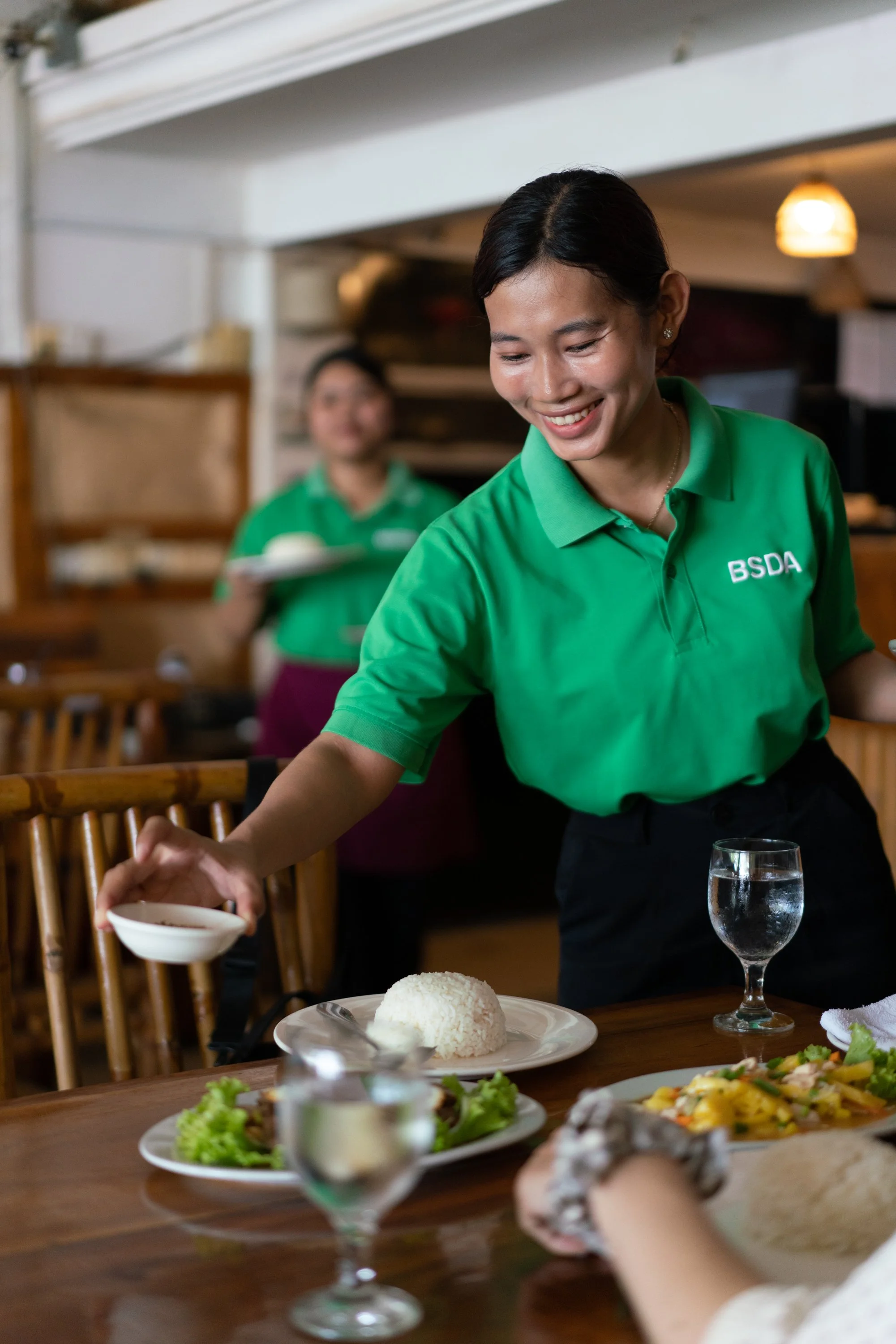 A bowl of spicy Thai yellow curry with vegetables and chicken, surrounded by fresh fruits and herbs on a bamboo mat.