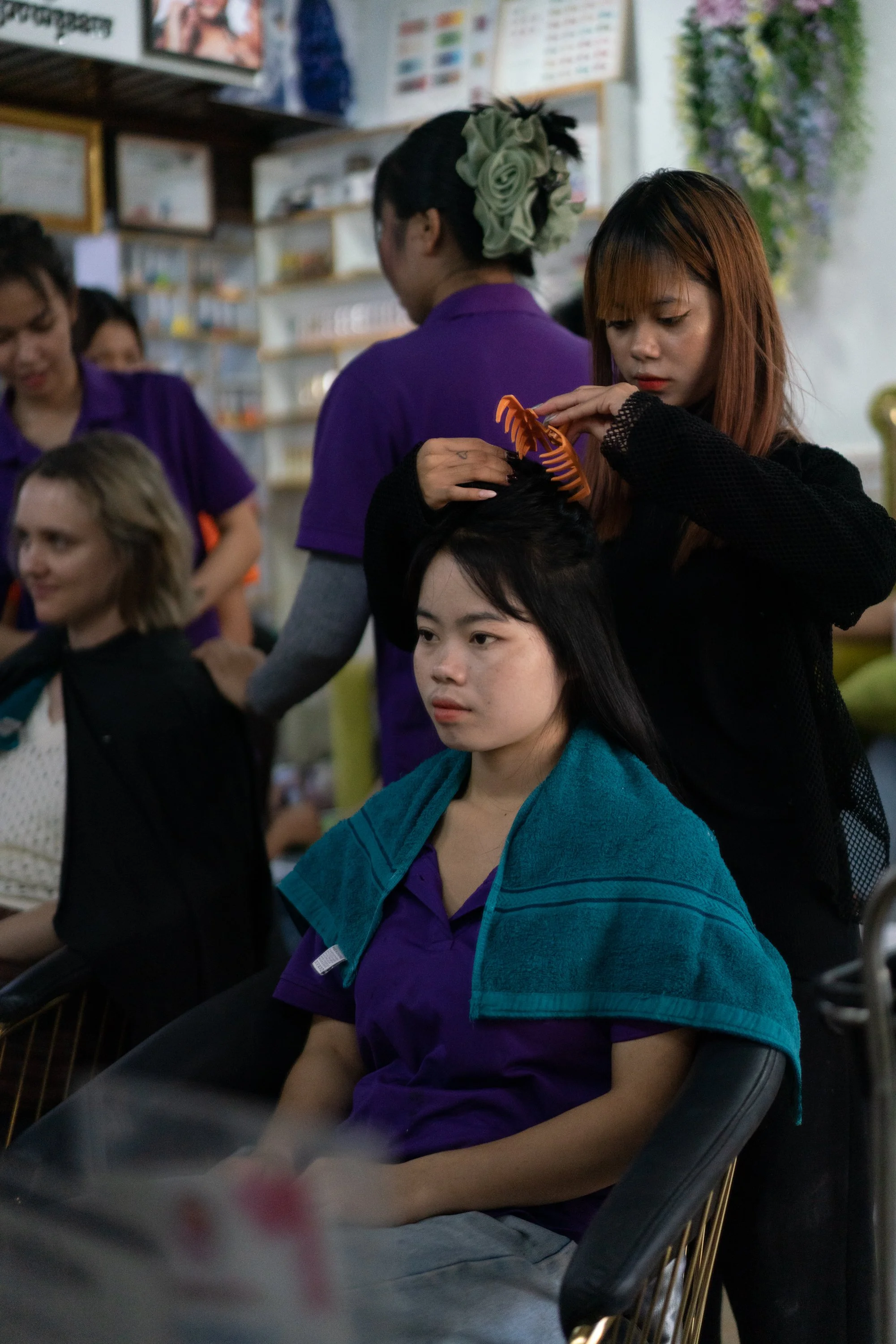 Three young people and a woman are gathered around a coffee roaster inside a bamboo structure, watching and operating the equipment.