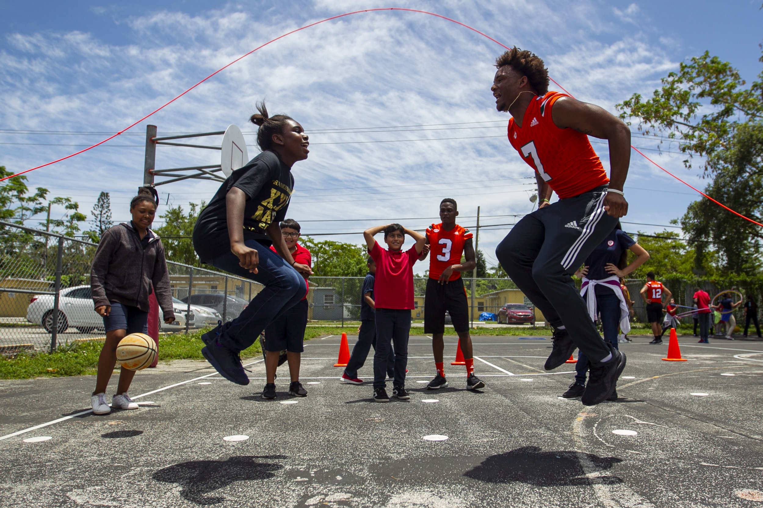  Karis Bellomy, left, jumps rope with University of Miami Hurricane player Brian Hightower (7) at Tucker Elementary School in Coconut Grove on Wednesday, May 23, 2018. The players participated in a day of community service at Tucker Elementary where 
