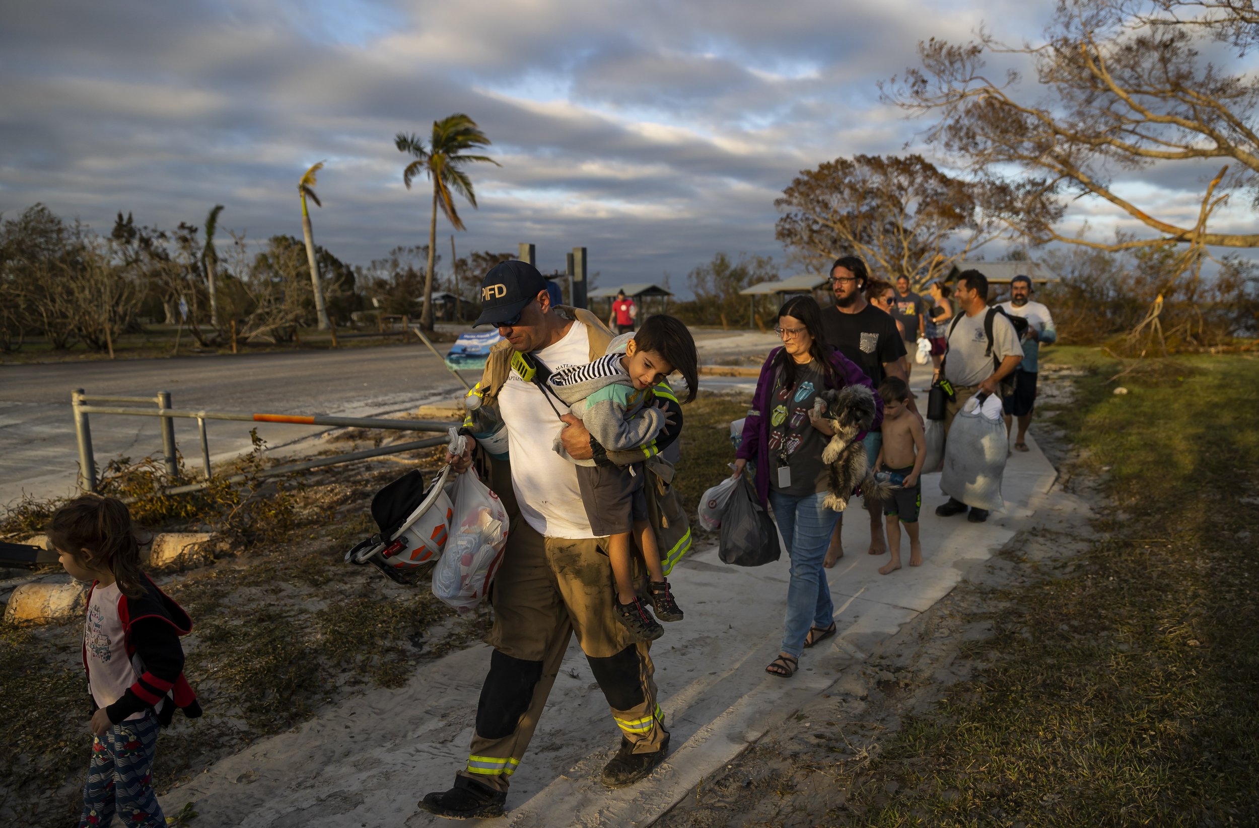 Pine Island Fire Department Captain Bobby Barr holds Greyson Ribas, 3, before ferrying him and residents of Matlacha across water due to broke sections of Pine Island Road on Thursday, Sept. 29, 2022,