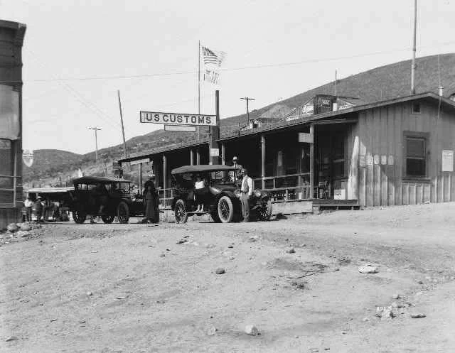 Photo of the San Ysidro border station between Tijuana and San Diego with cars parked on the dirt street in front of it, circa 1922
