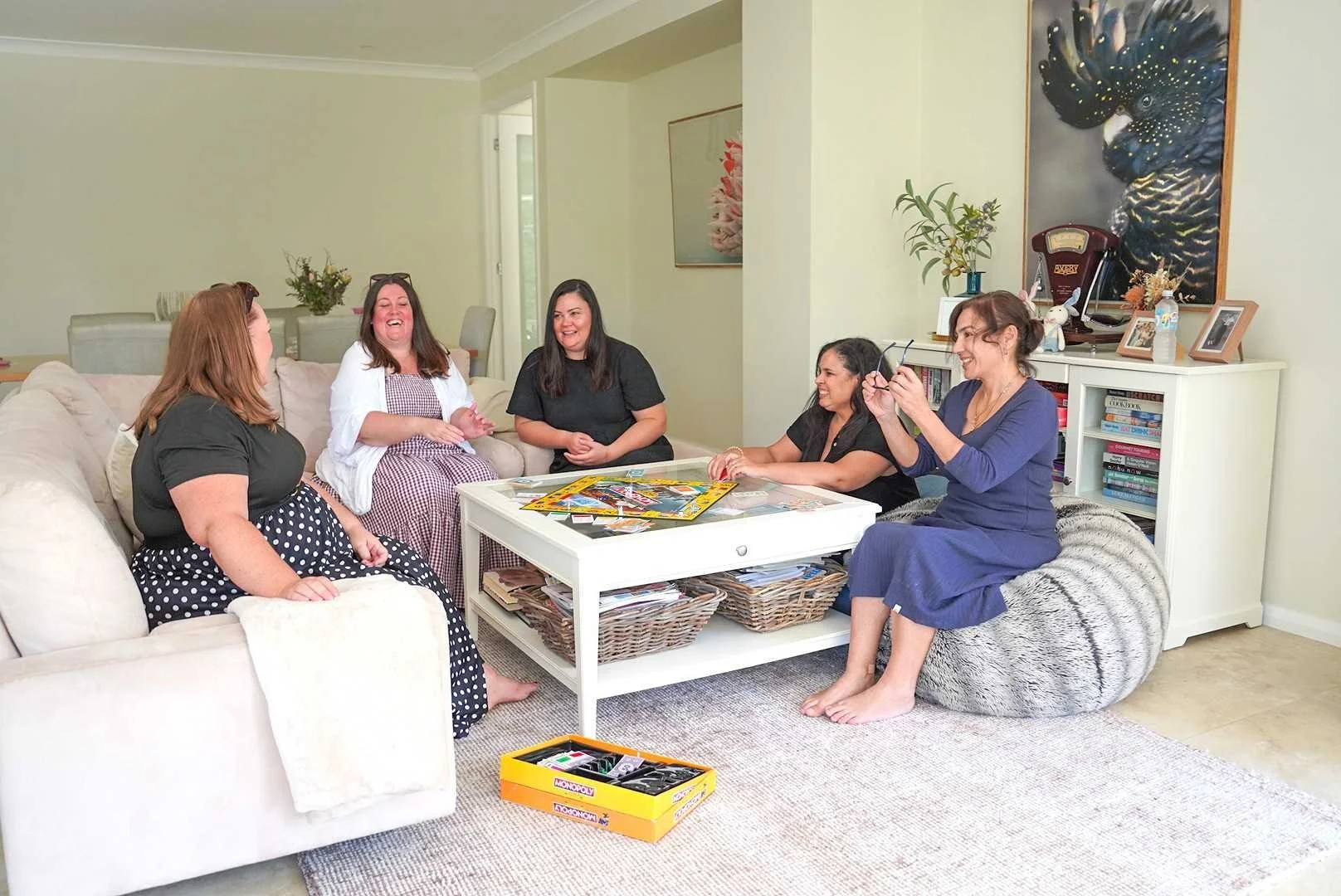 Five women enjoying a fun girls weekend at Dido’s Place, gathered in the spacious lounge room playing board games and relaxing together in stylish Hawkesbury group accommodation.