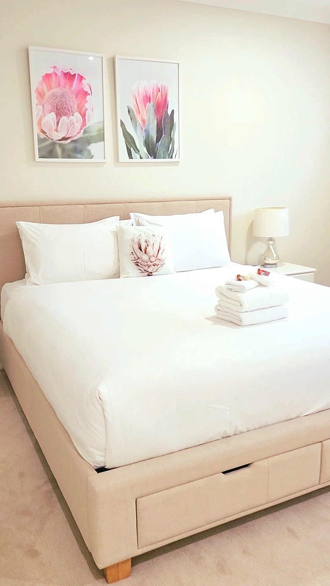 tylish bedroom at Dido’s Place featuring a queen bed with fresh white linen, bedside lamp, soft neutral décor and floral artwork, offering comfortable Hawkesbury accommodation for a relaxing country getaway.