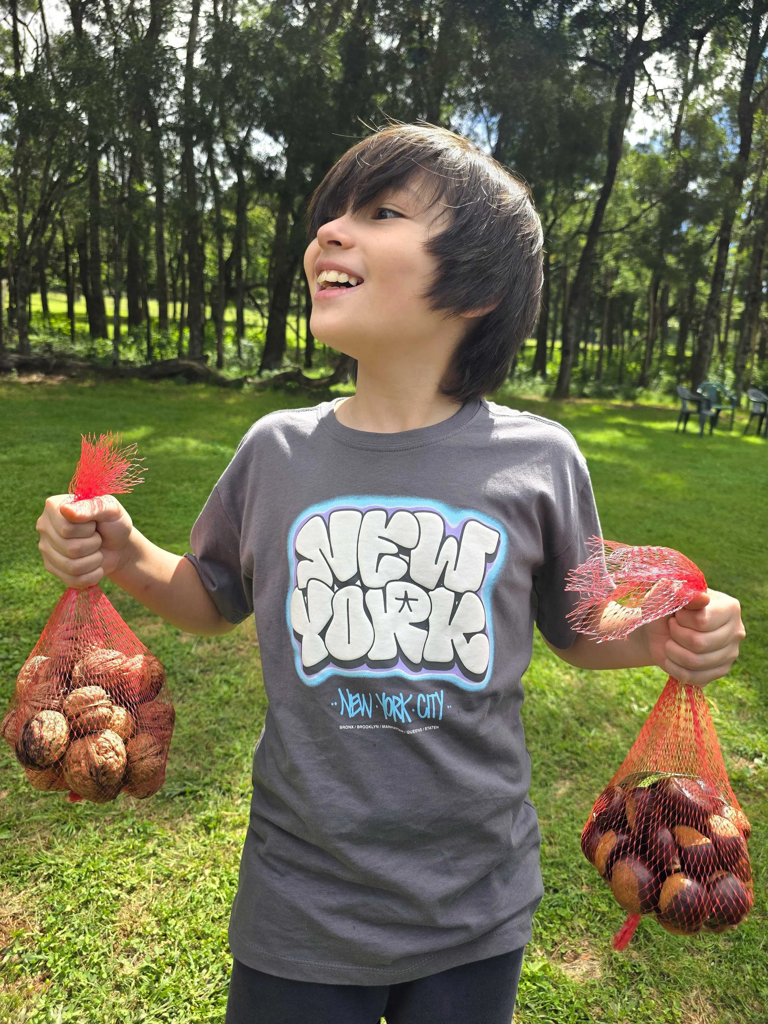 Child holding bags of freshly picked chestnuts and walnuts at Mt Irvine orchard during autumn near Bilpin and the Hawkesbury