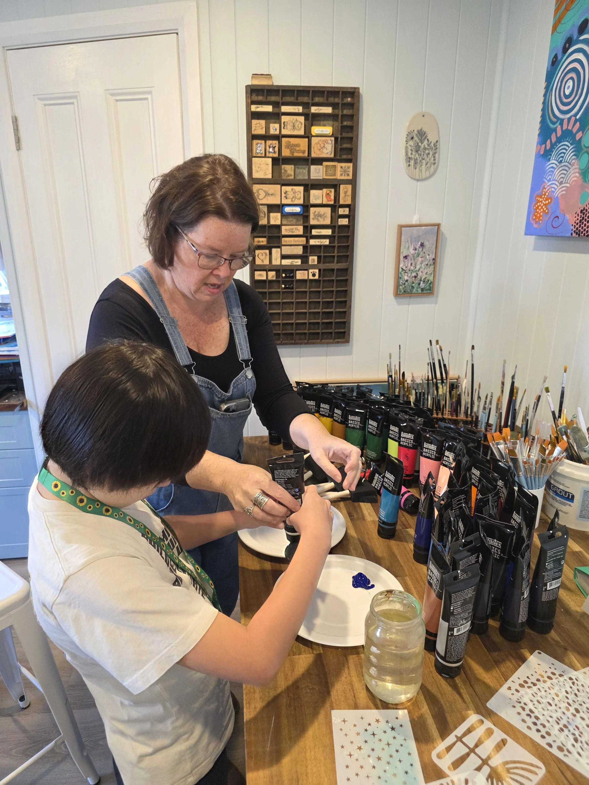 Child learning painting techniques with an art teacher during a school holiday craft camp in the Hawkesbury NSW