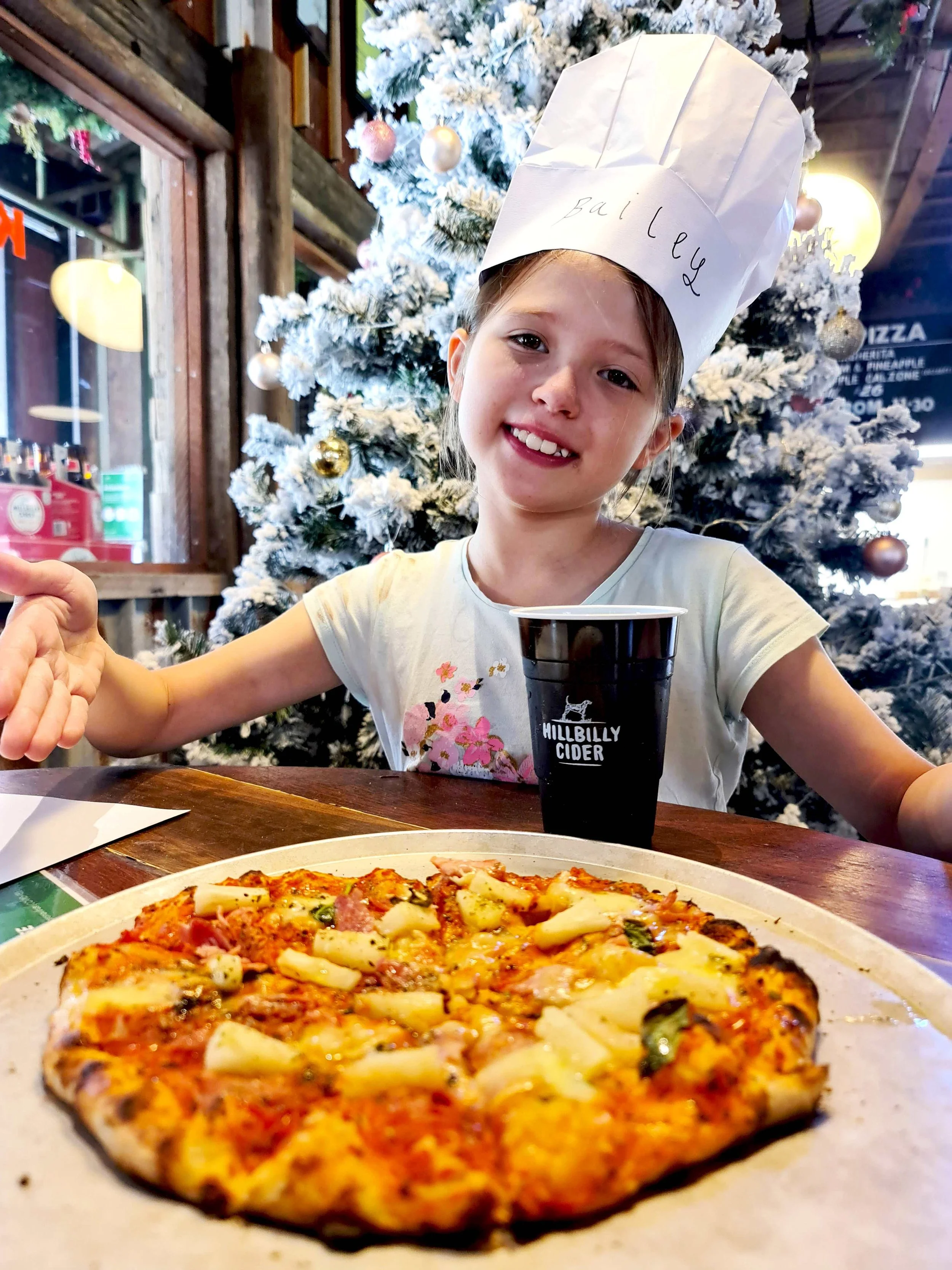 Child proudly showing their handmade pizza during a kids pizza making class at Hillbilly Cider in Bilpin, a popular school holiday activity in the Hawkesbury region.