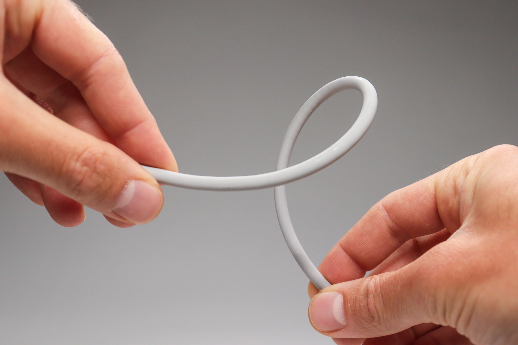 a photo of two hands flexing a rope of flexible polymer clay after it has been baked.