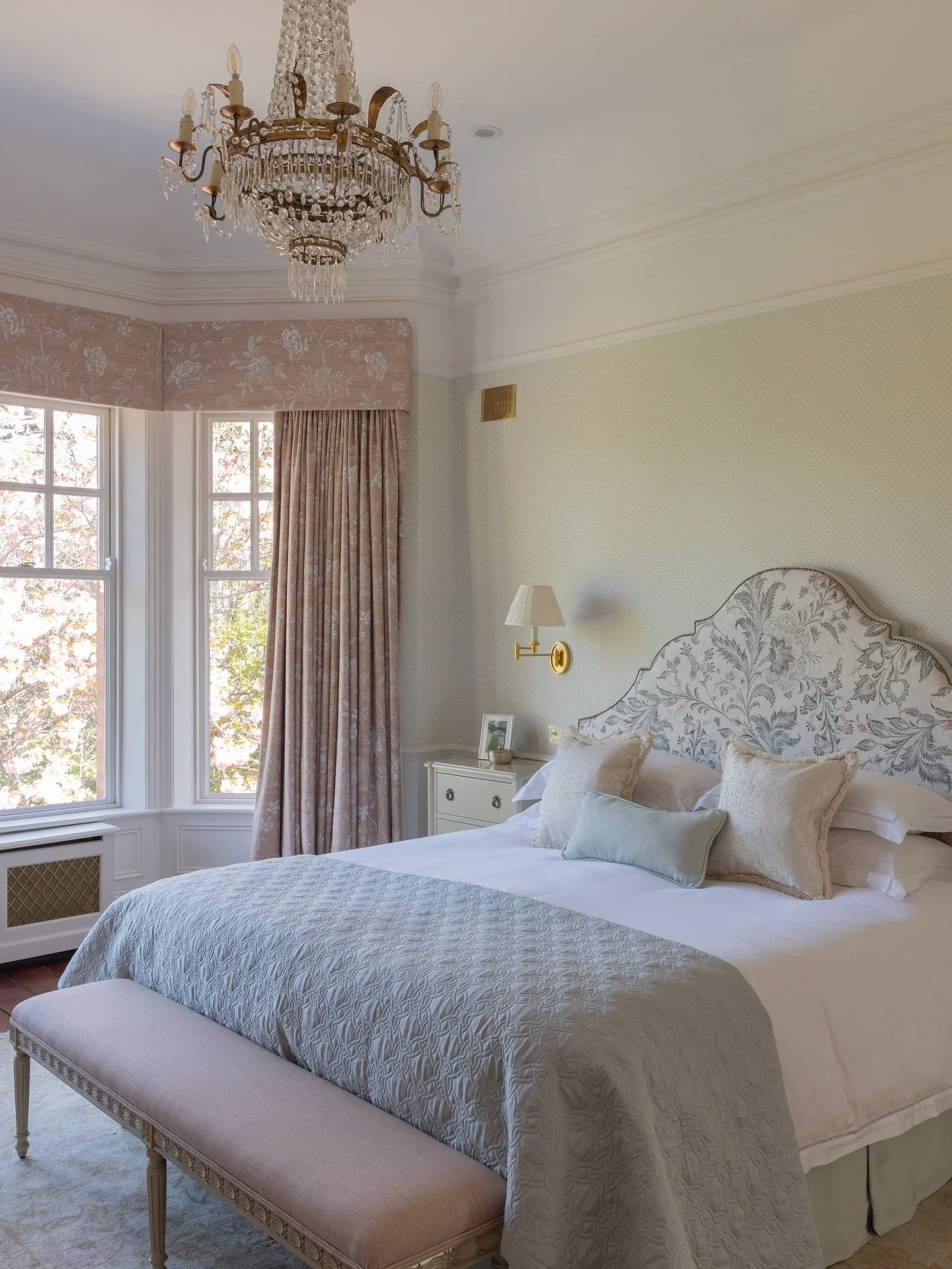 A soft, layered look in the Blossom Drive primary bedroom. Patterned wallpaper and panelling set a classic backdrop for the bespoke upholstered headboard and handcrafted nightstands. Every element was designed to feel calm, comfortable and quietly lu