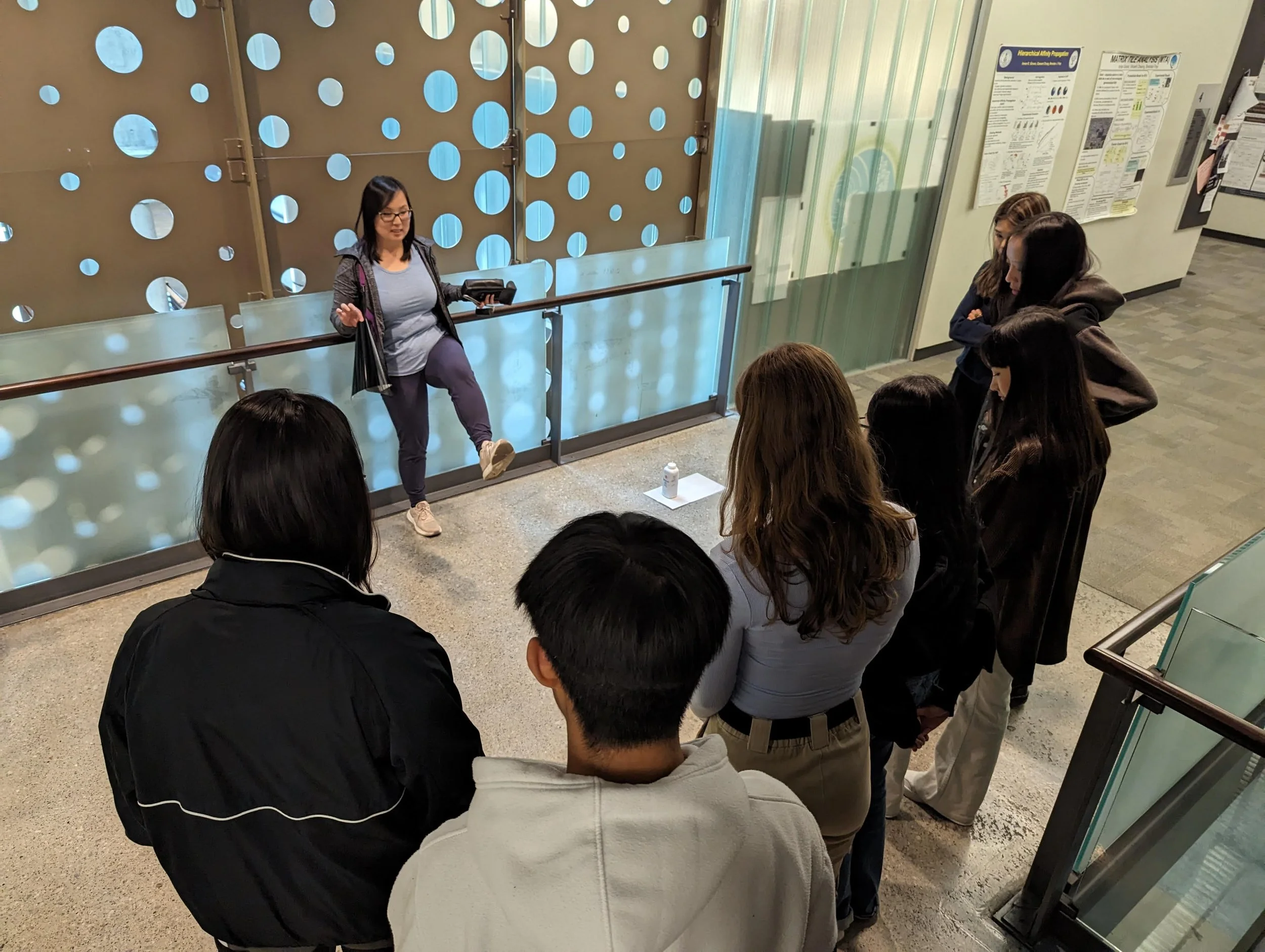 Vivienne Luk stands on one leg while demonstrating how to collect a shoe imprint for a group of students.