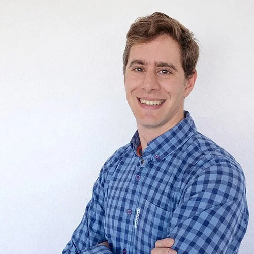 Daniel Gehrig smiles facing the camera with his arms folded across his chest.