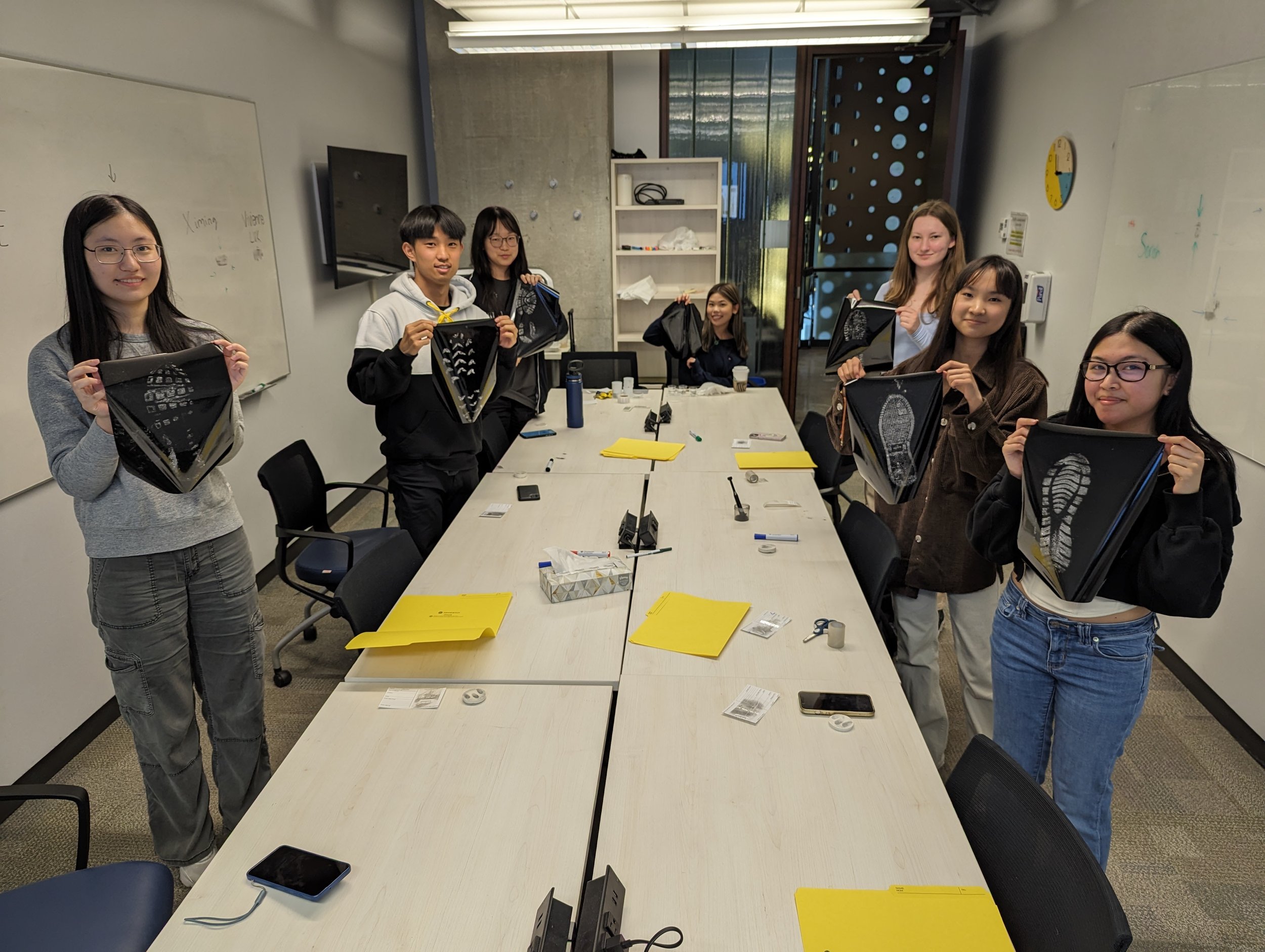 A group of students hold up individual shoe impressions.