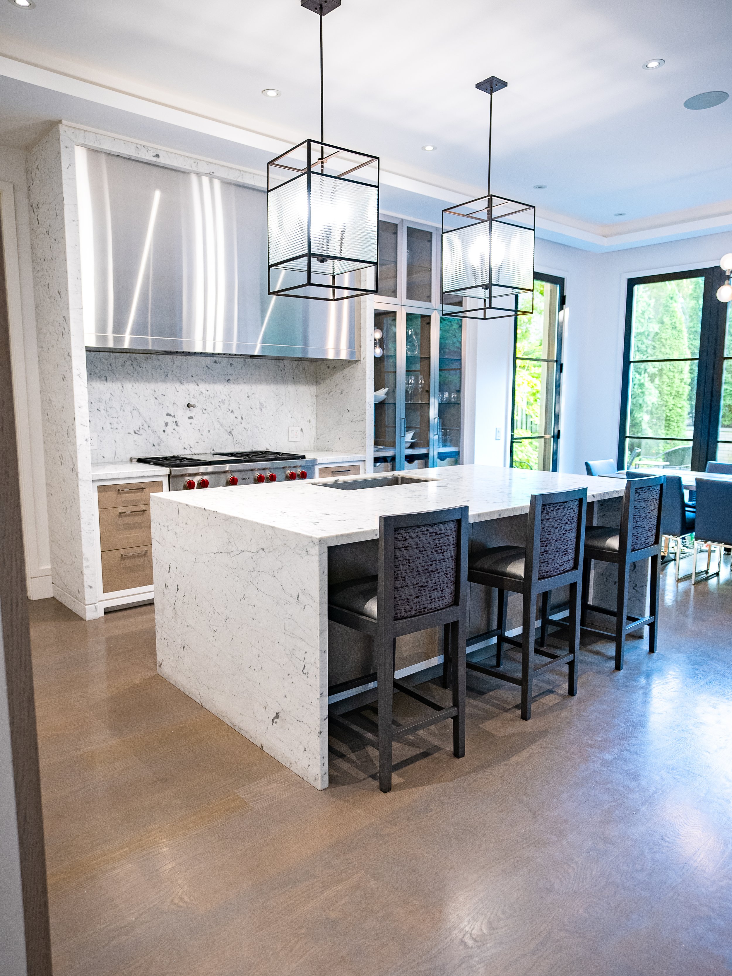  White Carrara Marble kitchen fully preserved with honed PROSHIELD: Island, waterfalls &amp; range. Gloria White Quartzite bathroom countertops, shower bench &amp; niche protected with polished PROSHIELD. 