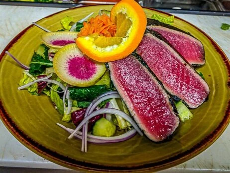 Sesame-crusted seared ahi tuna steak sliced over a fresh Japanese garden salad with edamame and ginger dressing.