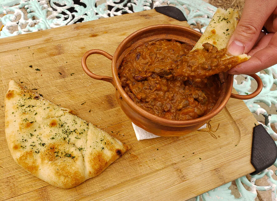 Traditional Indian Dal Makhani with Garlic Naan served in a copper pot – New Delhi Food Guide.