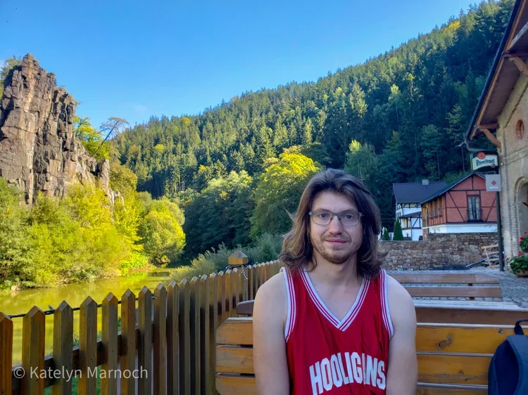 A hiker resting at an outdoor riverside pub in the Slavkov Forest region.