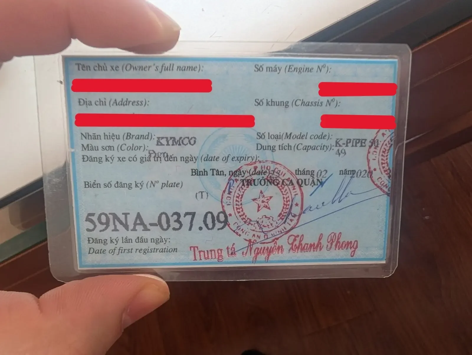 A de-identified blue vehicle registration card (Cà Vẹt) for a 50cc Kymco motorbike in Vietnam, showing redacted owner information while keeping the city prefix and displacement fields visible for educational purposes.