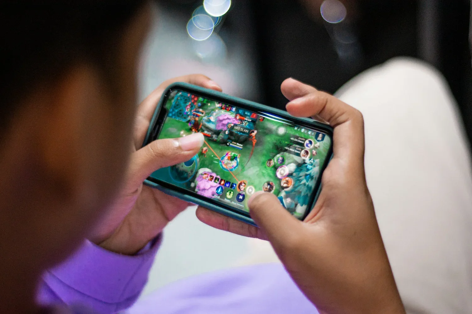 Close-up of a person playing Mobile Legends: Bang Bang on a smartphone; illustrating the dominant mobile MOBA culture and "mabar" lifestyle in Southeast Asia.