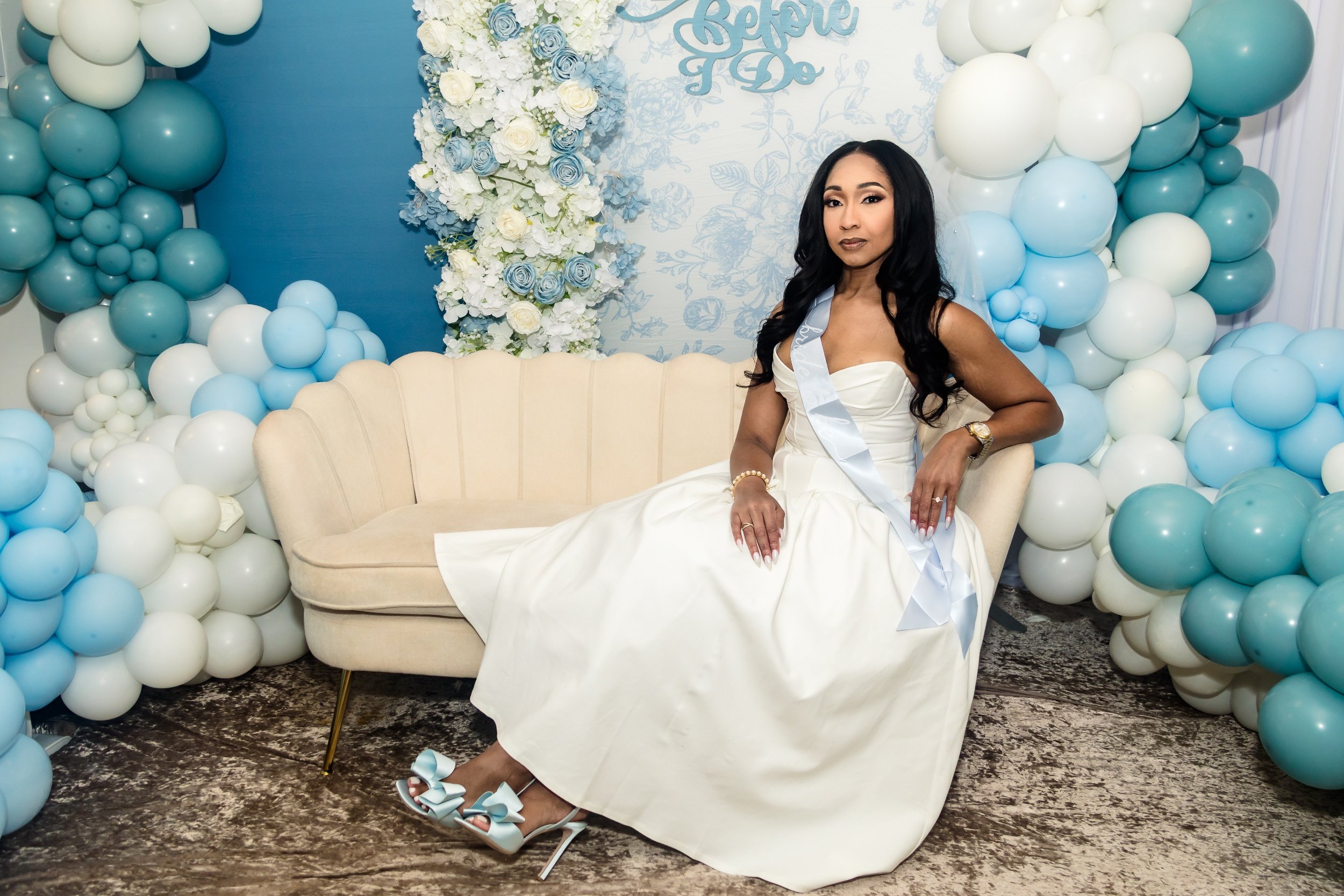 A beautiful bride-to-be sits on a vintage cream loveseat at her "something blue before I do" bridal shower