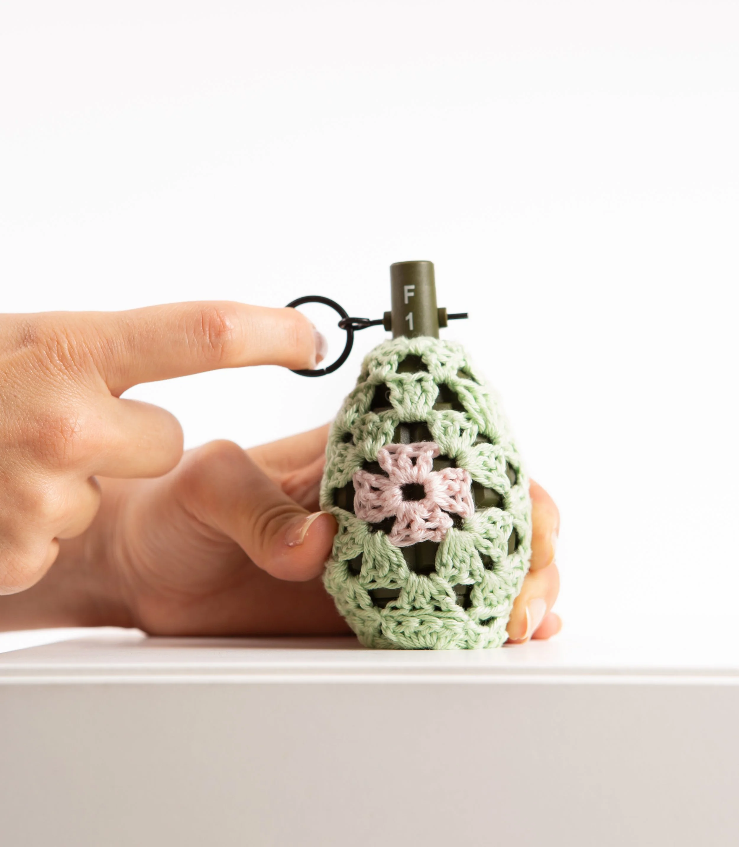 Green grenade hand-crocheted textile sculpture held in hand by Sophie Inard Paris