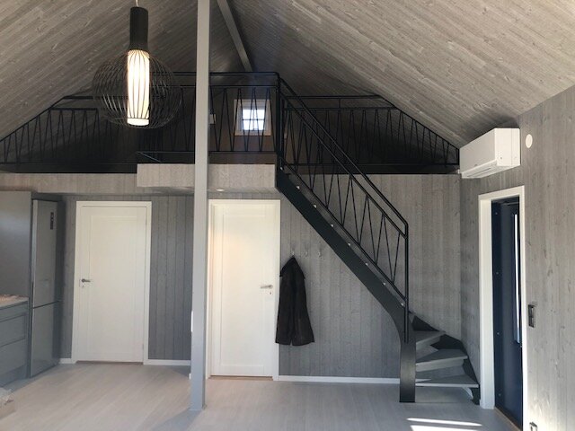 fritidshus-etage-etagevåning-svart-trappa-stål-vita-dörrar-modern-lampa-ytterdörr