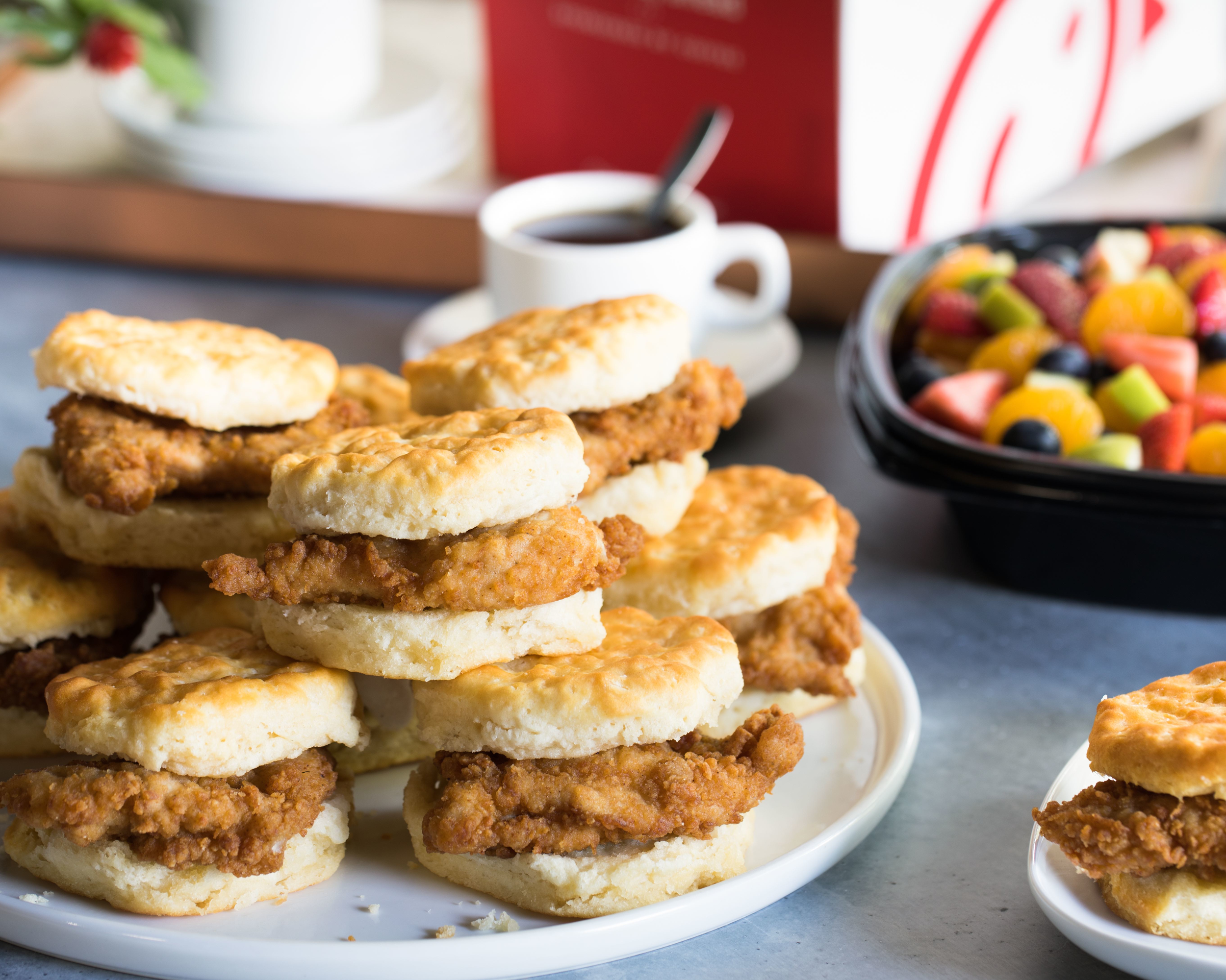 Chick-fil-A Chicken Biscuits on a plate with fruit and coffee.