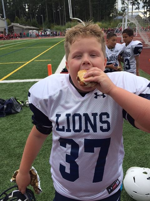 Young football player eating chicken biscuit