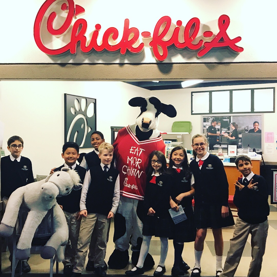 Group of students with Chick-fil-A cow in front of counter