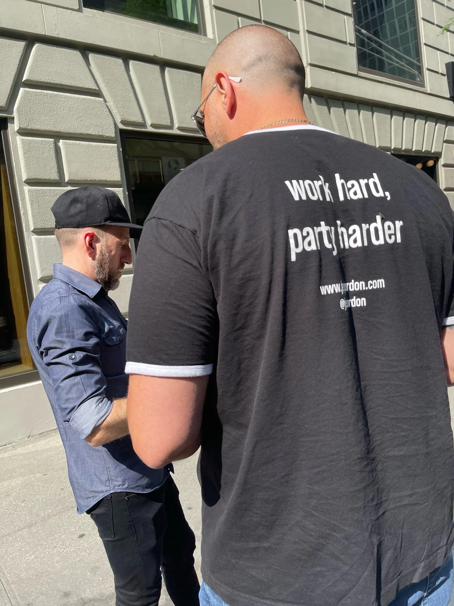 Event planner Joe standing on a NYC street with employee going over details