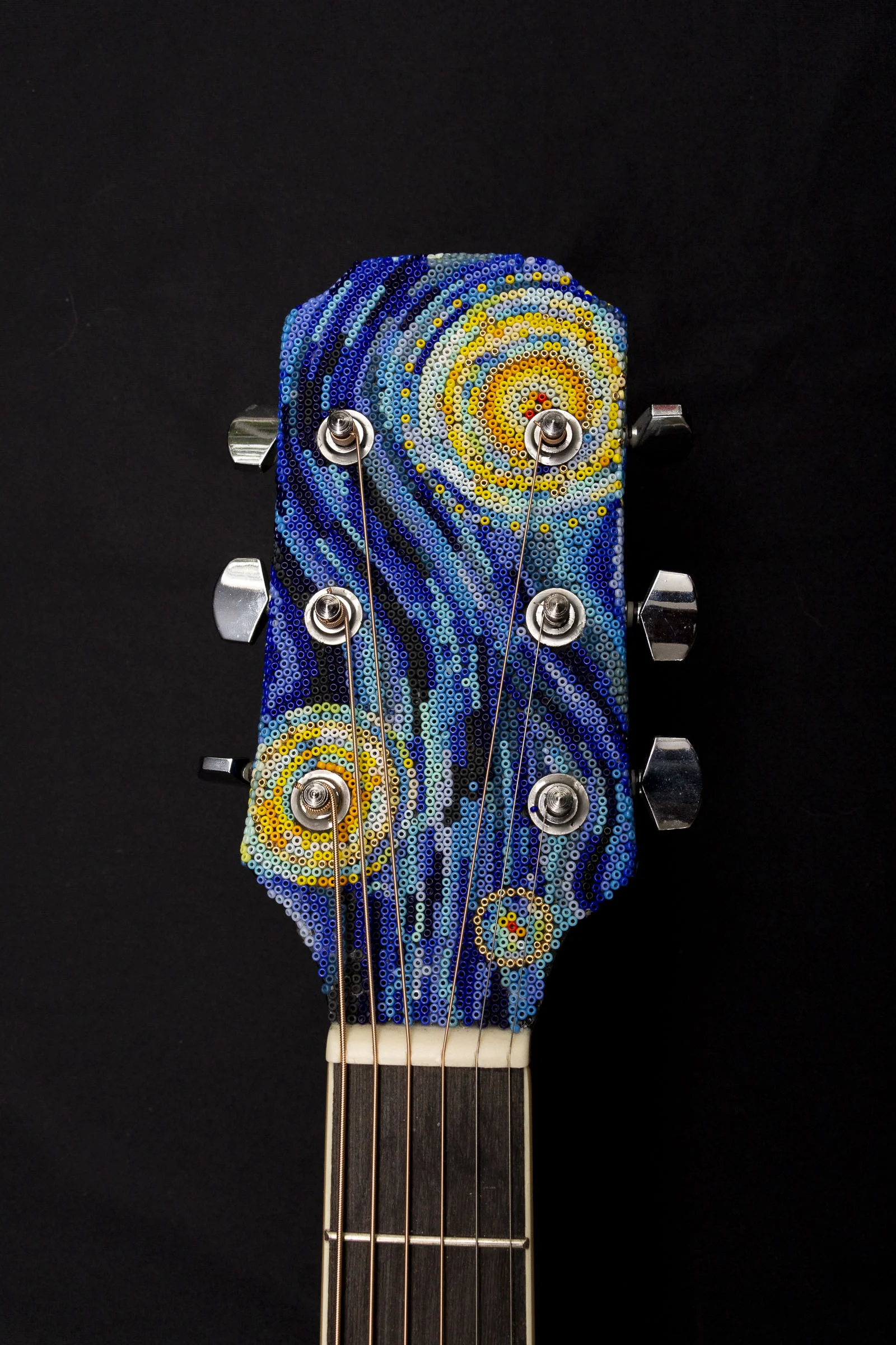  The beadwork continues to the headstock of the guitar and wrapps 90 degrees around the edges. 