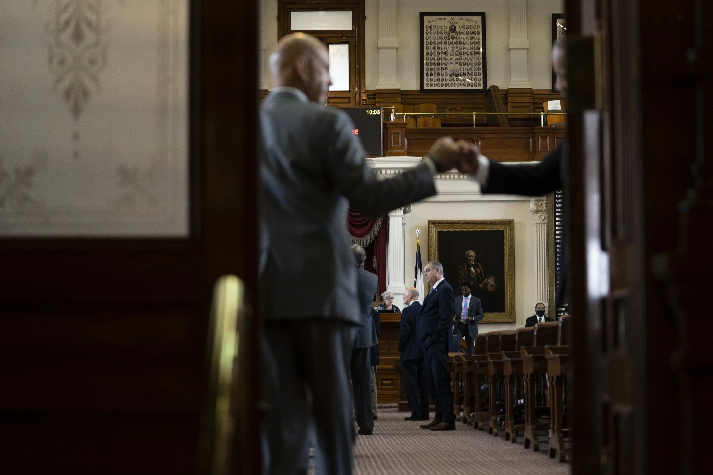 A Texas legislator fist bumps with a House Administration staff person as they enter the House Chamber on Aug. 11, 2021. 