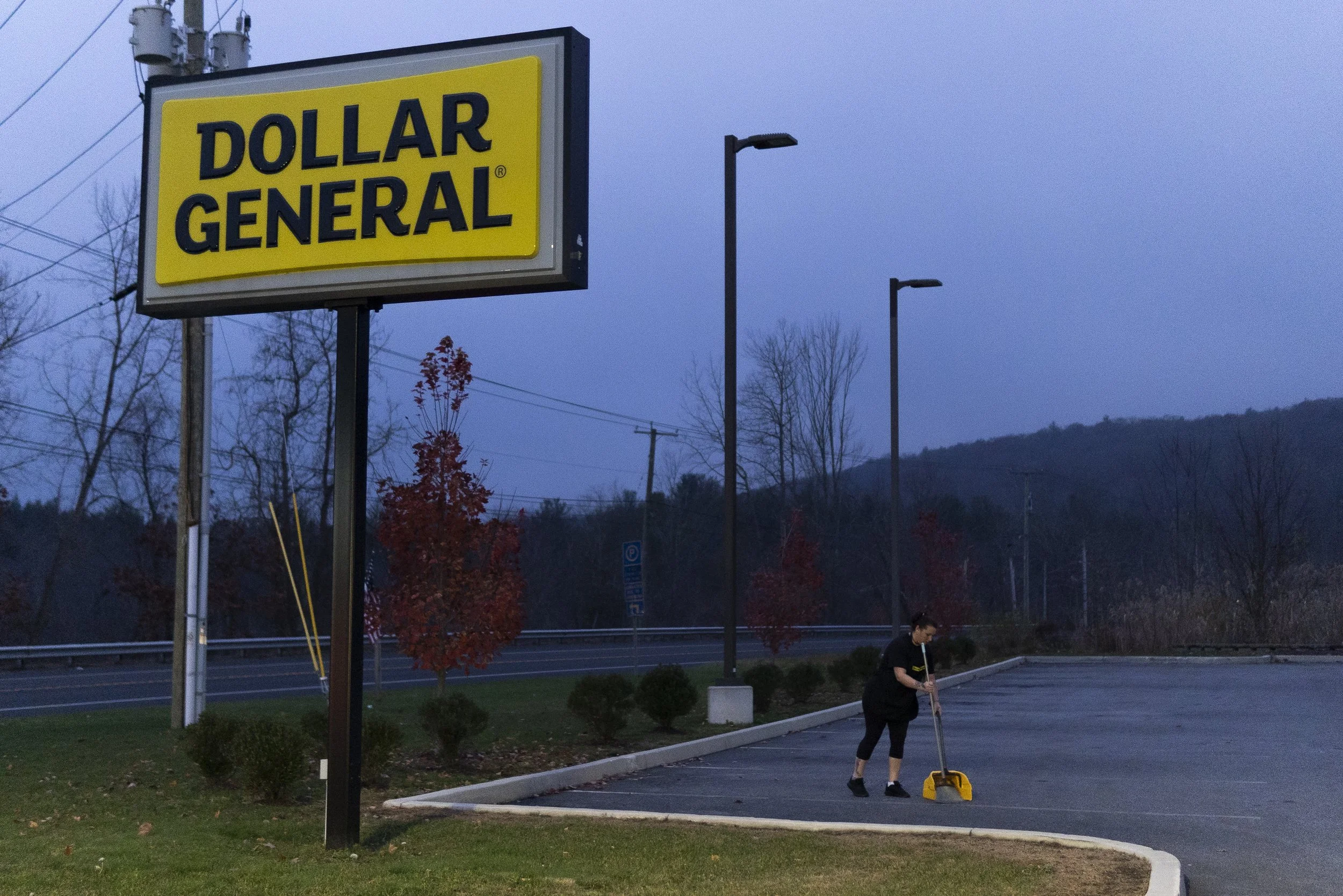 Shellie Parsons, 37, sweeps the parking lot for trash and cigarette butts at the Dollar General that she works at in Barkhamsted, CT. While the parking lot is supposed to be swept the night before by a coworker, Shellie often has to do it during her 