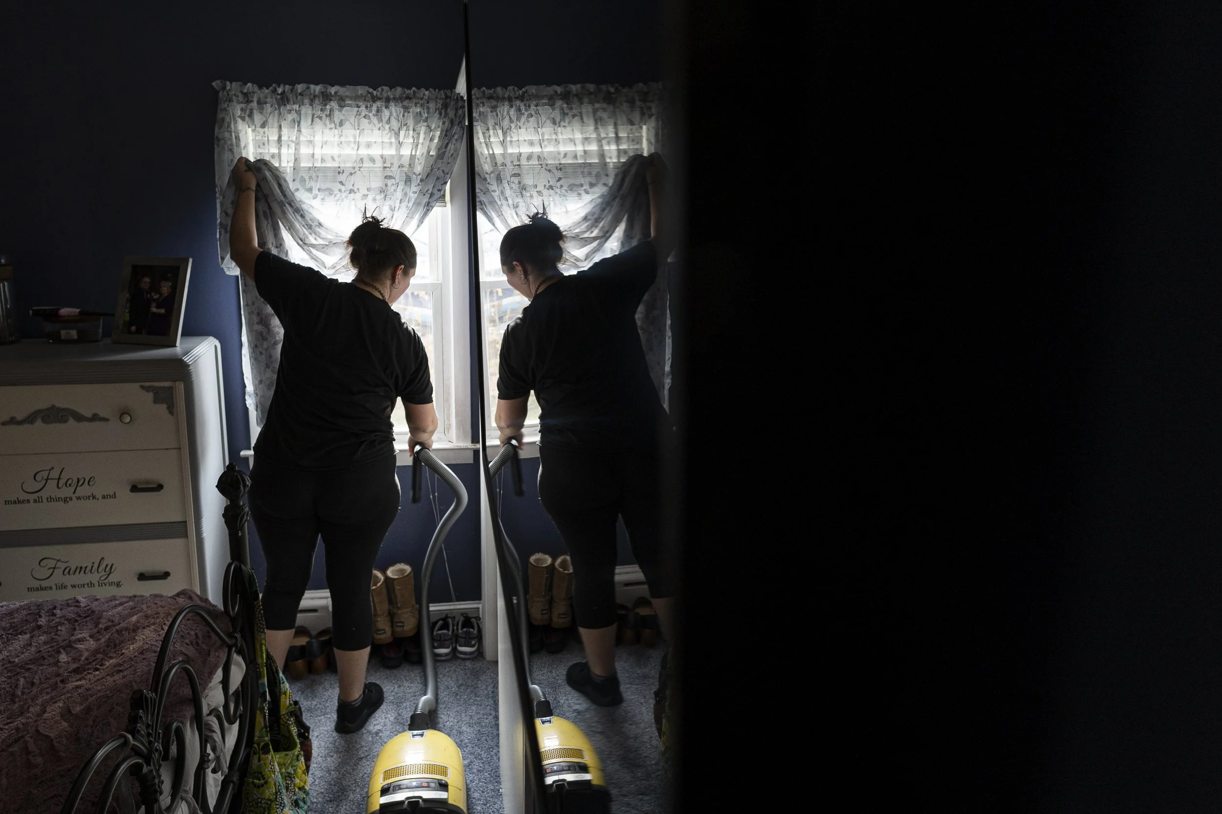 Shellie vacuums the bedroom of a client’s home. On her days off from Dollar General, Shellie cleans houses to afford the lawyer assisting her in her custody battle.