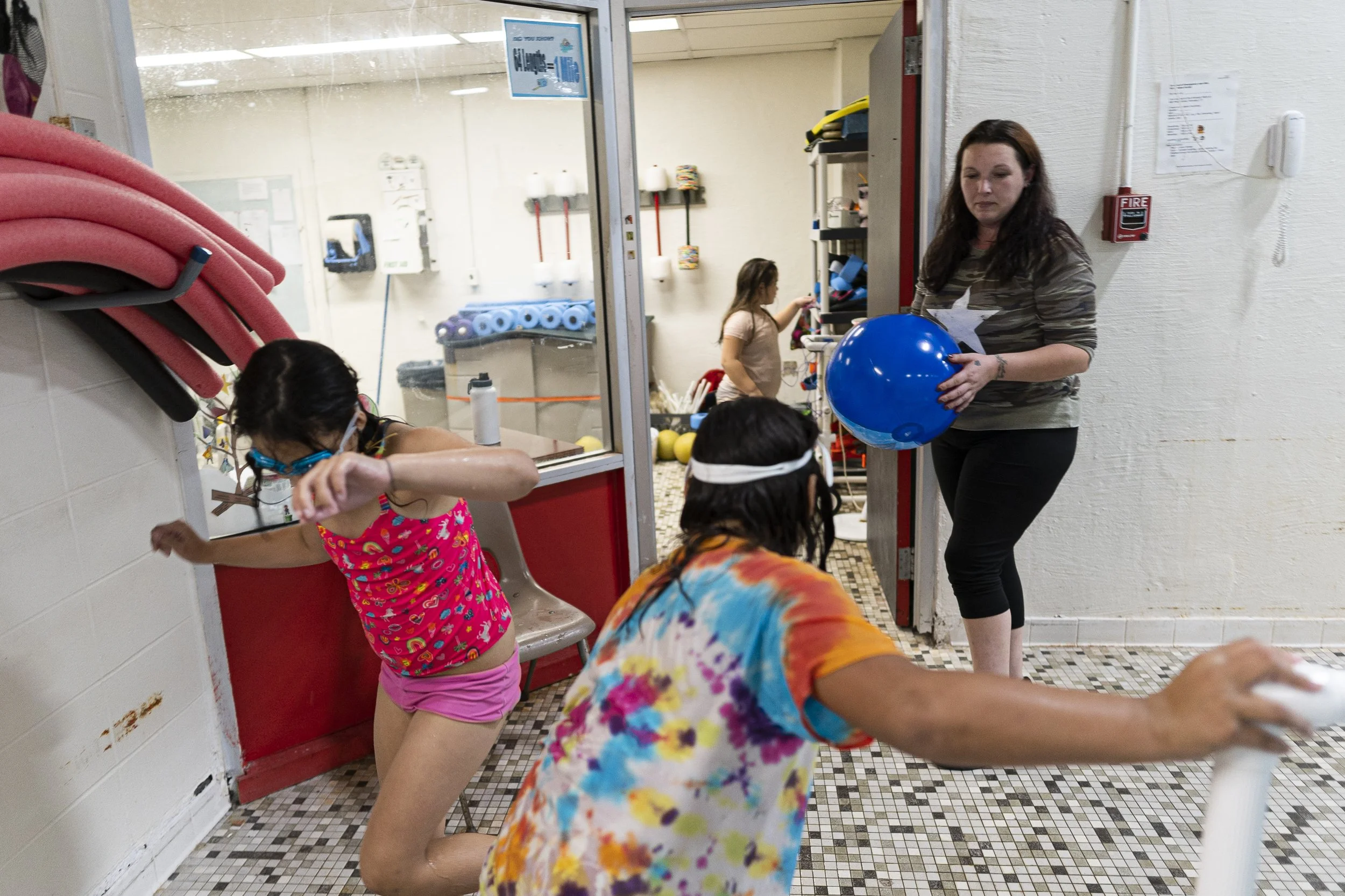 Selenia and Emma Velez play with their swimming flippers while Bella picks out other swimming toys, and Shellie holds an inflatable ball at the Winsted YMCA. Shellie was able to afford $15 for the girls to swim in one lane for an hour.