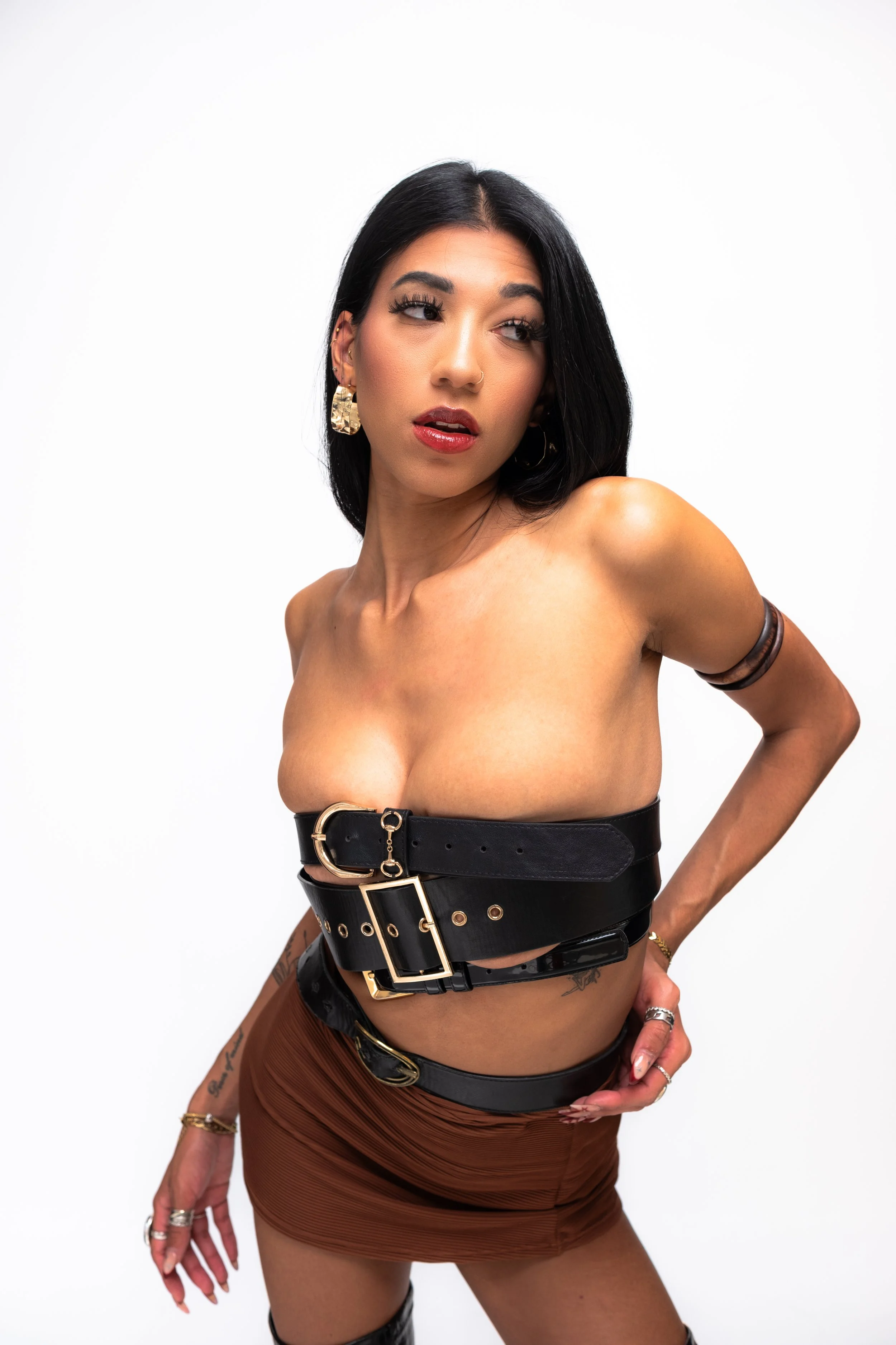 A woman with black hair and earrings posing against a plain white background.