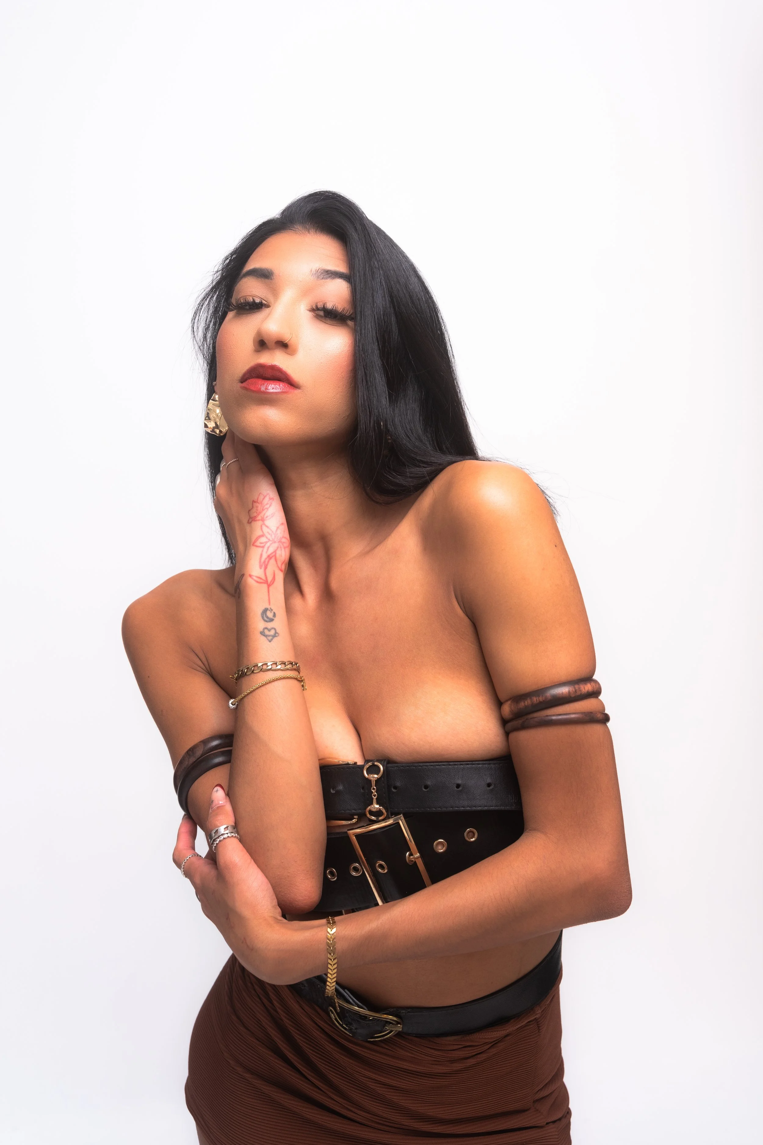 Portrait of a woman with dark hair, wearing jewelry, in front of a white background.