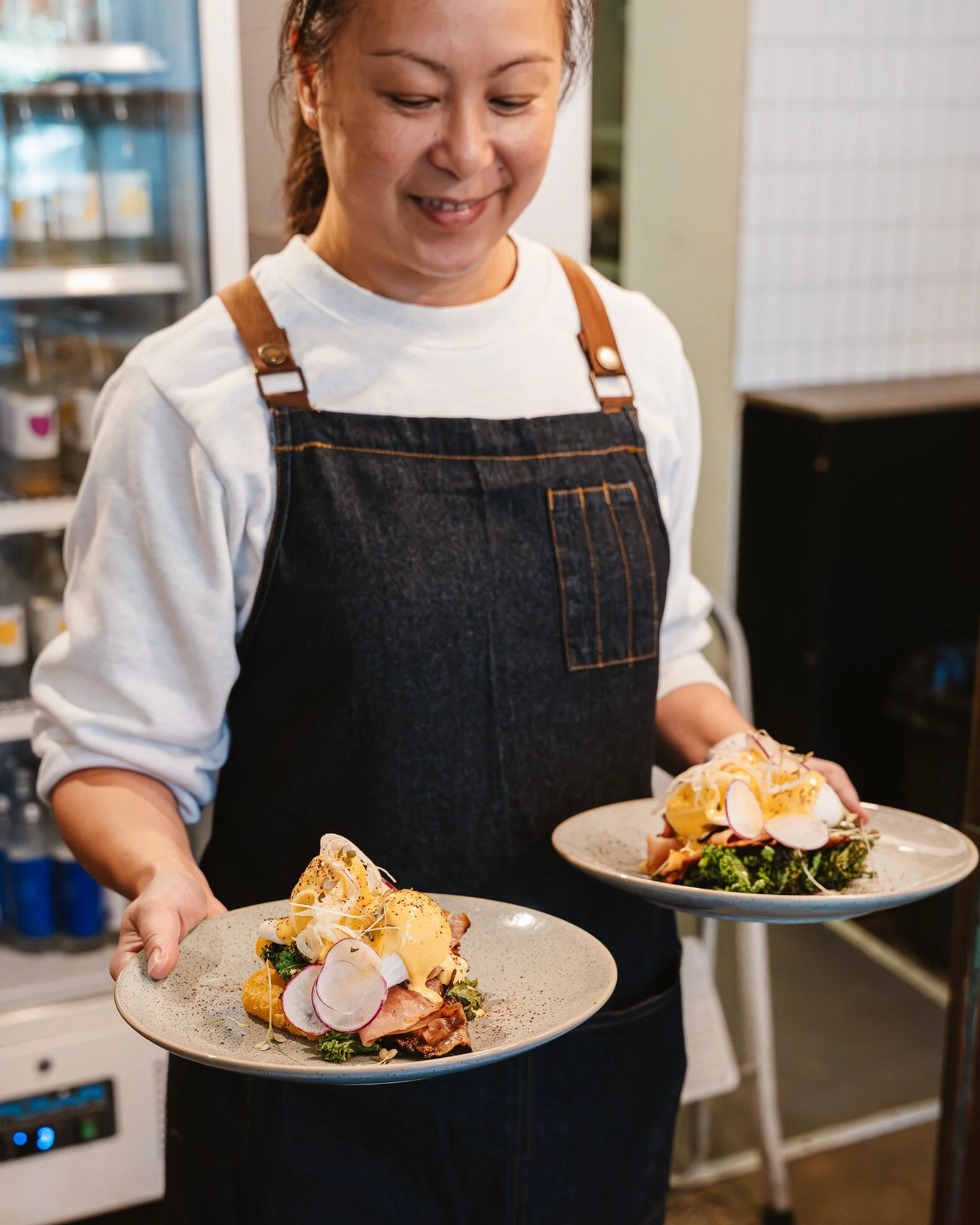 Marché Café staff carrying two plates of Eggs Benedict to a table in Hawthorn