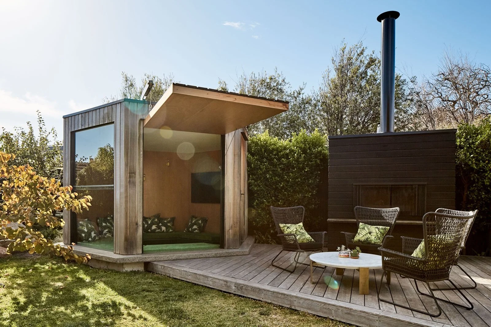 Outdoor room with lift up wall opening onto a deck with cooking fire