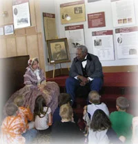 Volunteers interpret historic figures with a group of school children.
