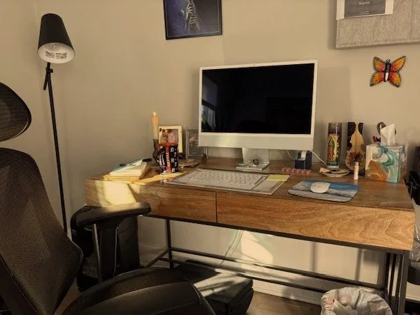 A tidy office setup in Labyrinth PLLC with a wooden desk, monitor, keyboard, office chair, lamp, and various personal items including books, tissues, and decor.