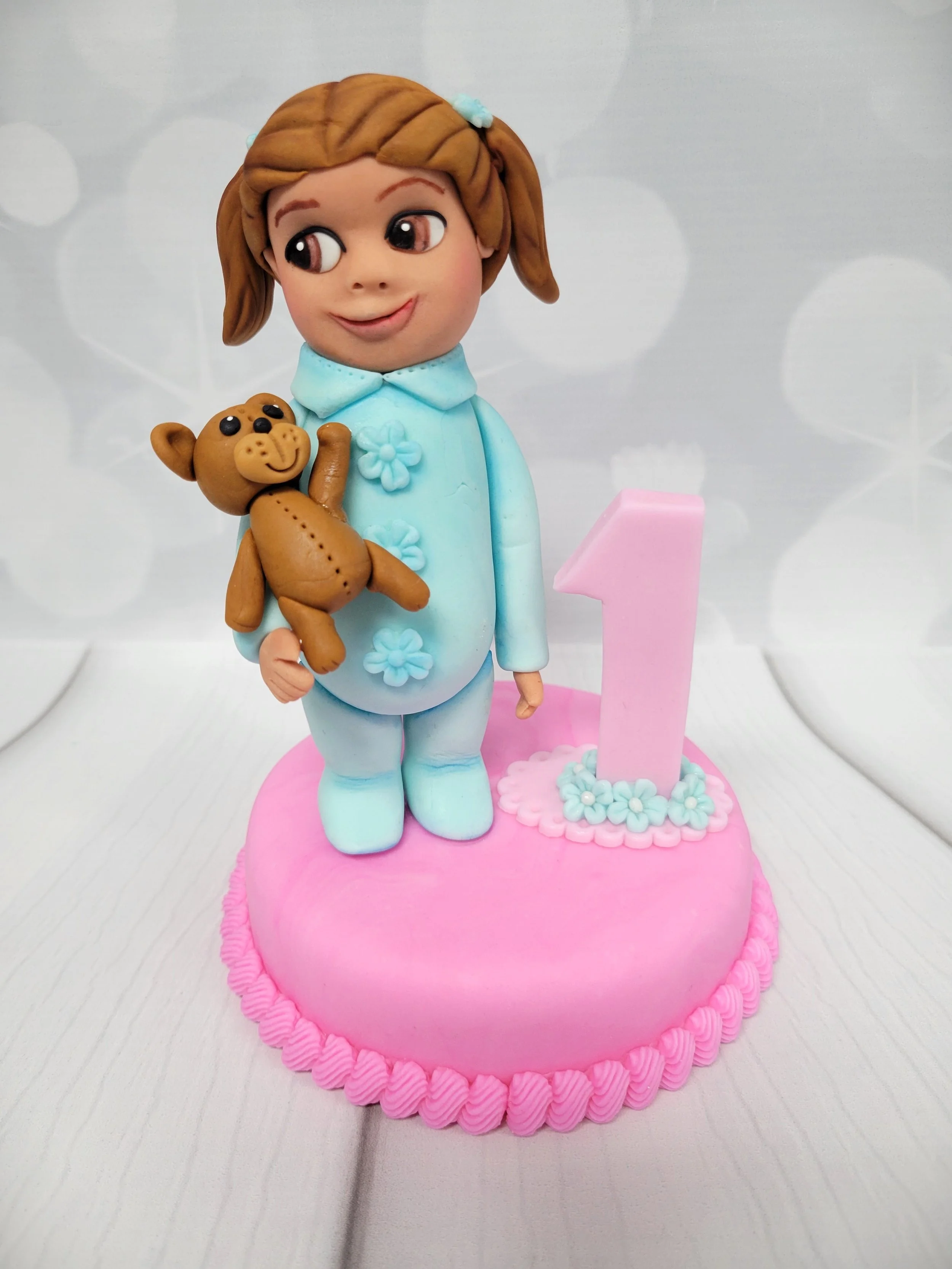 Cake topper of a baby girl in a onesie for her first birthday
