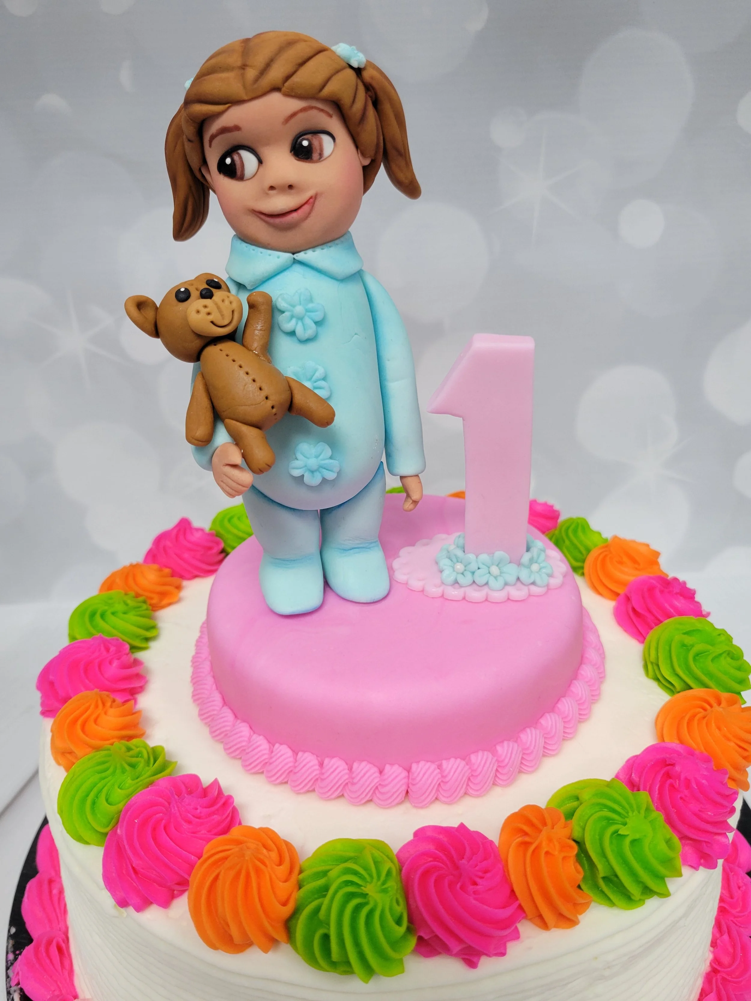 Cake topper of a baby girl celebrating her 1st birthday in a onesie