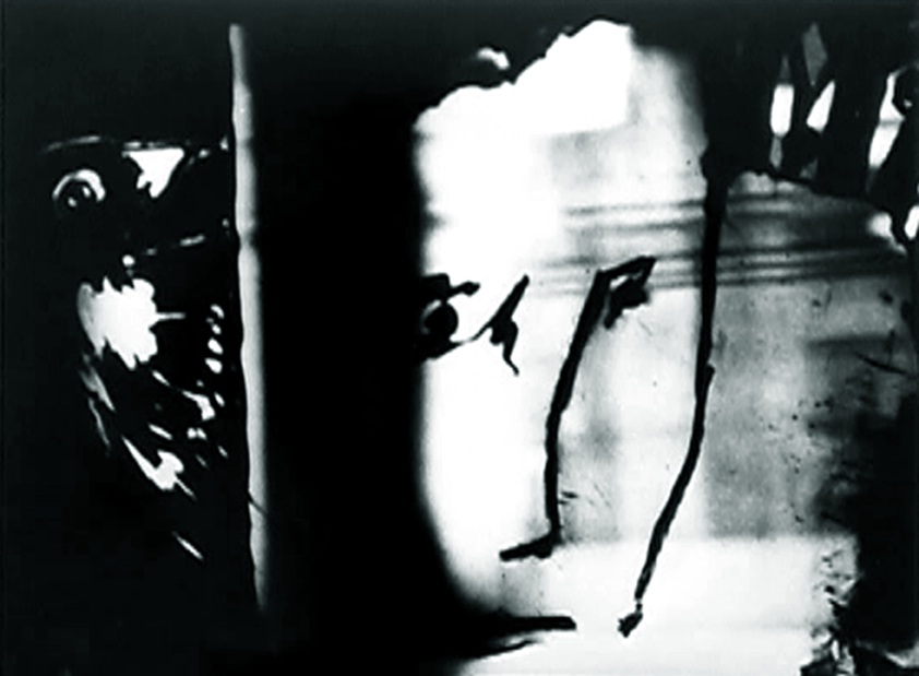  Lis Rhodes,  A Cold Draft  (still), 1988. Courtesy of the artist. A still from the film, showing an abstract image in black, white and shades of grey. Some of the marks approach the look of writing but no words can be read.   