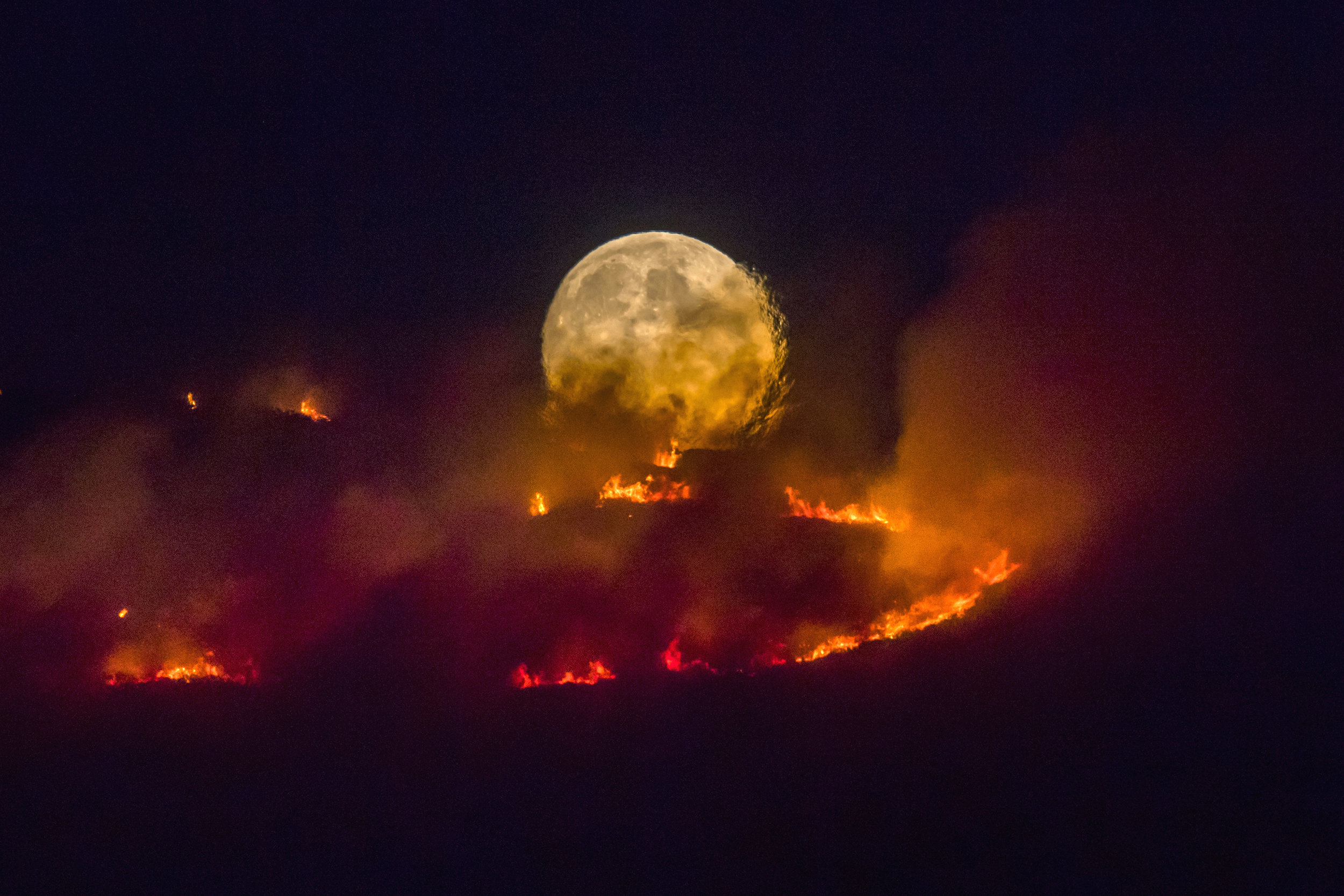  The full moon rises behind burning moorland as a large wildfire sweeps across the moors between Dovestones and Buckton Vale in Stalybridge, Greater Manchester.
Photo by Anthony Devlin, 26 June 2018
 