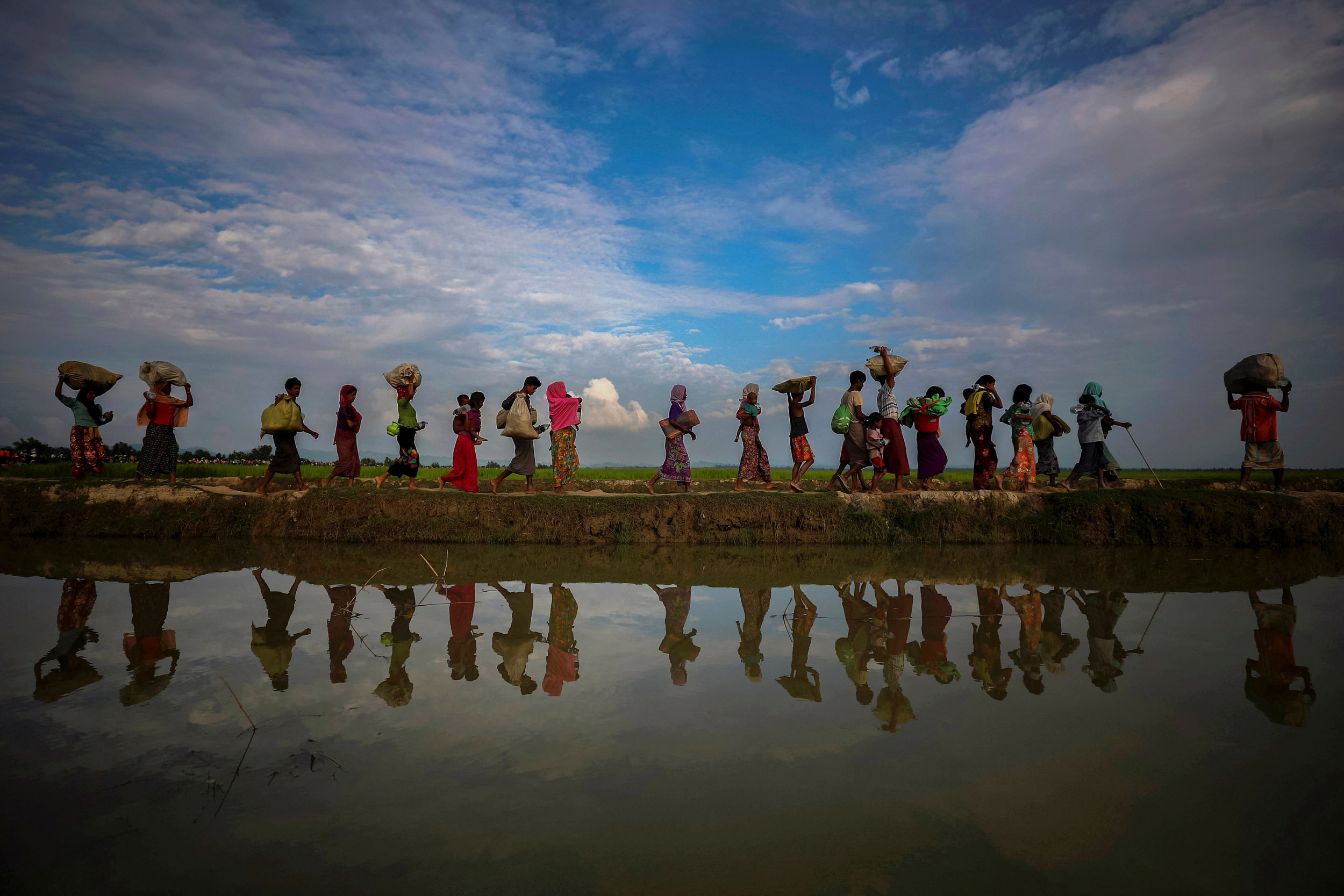  Rohingya refugees are reflected in rain water along an embankment next to paddy fields after fleeing from Myanmar into Palang Khali, near Cox's Bazar, Bangladesh.
Photo by Hannah McKay, 02 November 2017
 