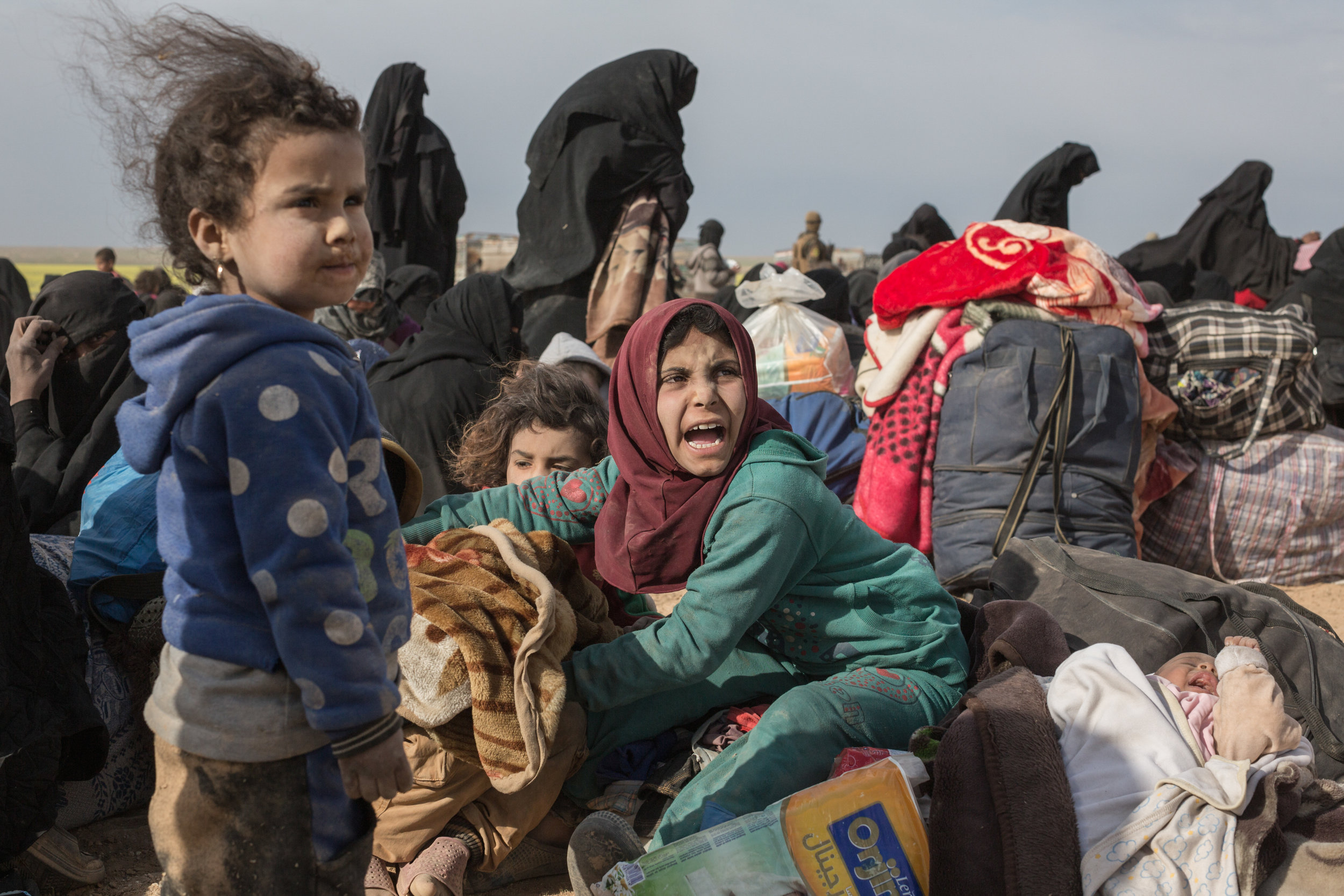  Civilians fleeing from ISIL's last remaining territory in Syria after two days of heavy fighting wait at a gathering point before being taken to internment camp, near Baghuz, in north eastern Syria.
Photo by Sam Tarling, 05 March 2019
 