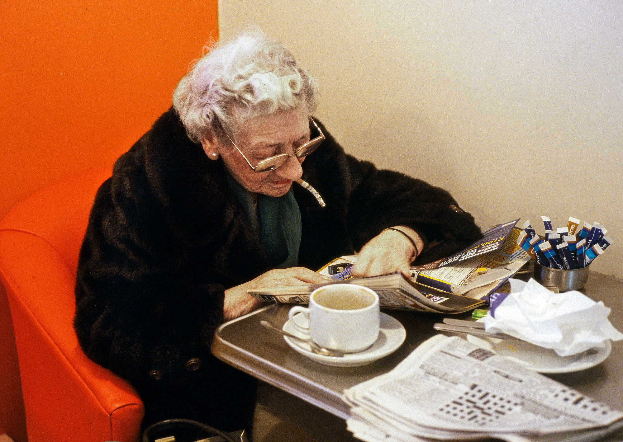  An elderly lady sits in a cafe engrossed in her puzzle magazines oblivious to the length of her cigarette ash. Ham, Surrey. Photo: David Levenson, 01 June 2000 