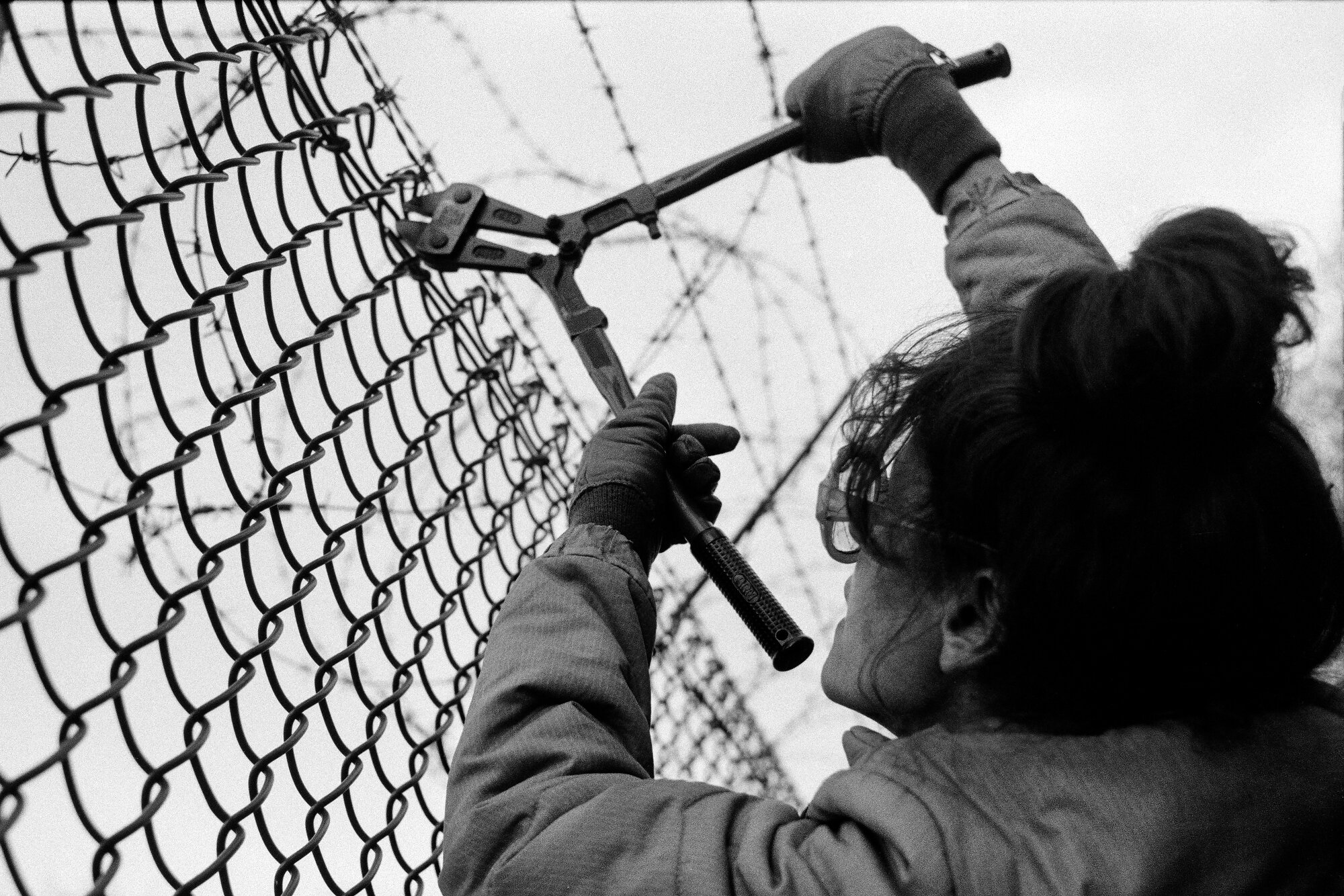  A member of the Greenham Common Women's Peace Camp cuts the fence around the nuclear base as their invasion of the site begins.  Photo: David Hoffman, 29 October 1983 