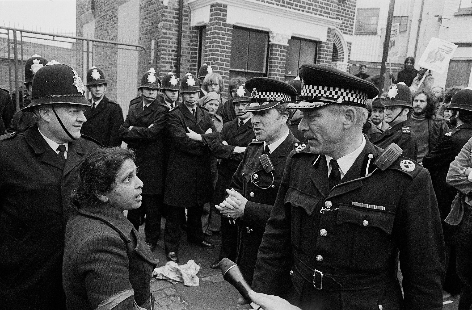  Jayaben Desai, a leader of a small band of strikers fighting the Grunwick film processing company for union recognition, is confronted by senior Police officers outside the company’s premises in Dollis Hill, London. Photo: Andrew Wiard, 13 June 1977