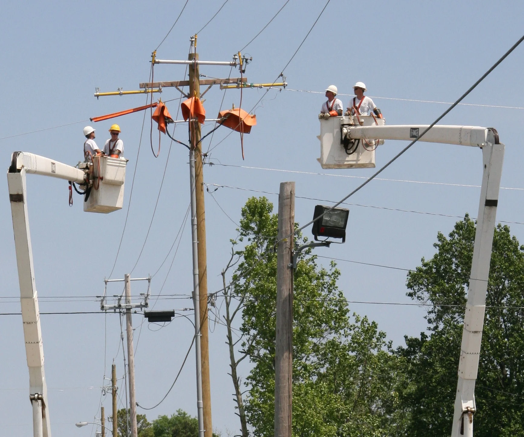 electrical companies in bucket trucks doing some telephone pole maintenance
